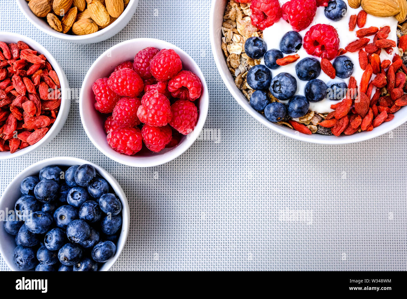 Una sana colazione vegetariana ciotola di muesli con frutta fresca i dadi e yogurt in bianco Bocce Foto Stock
