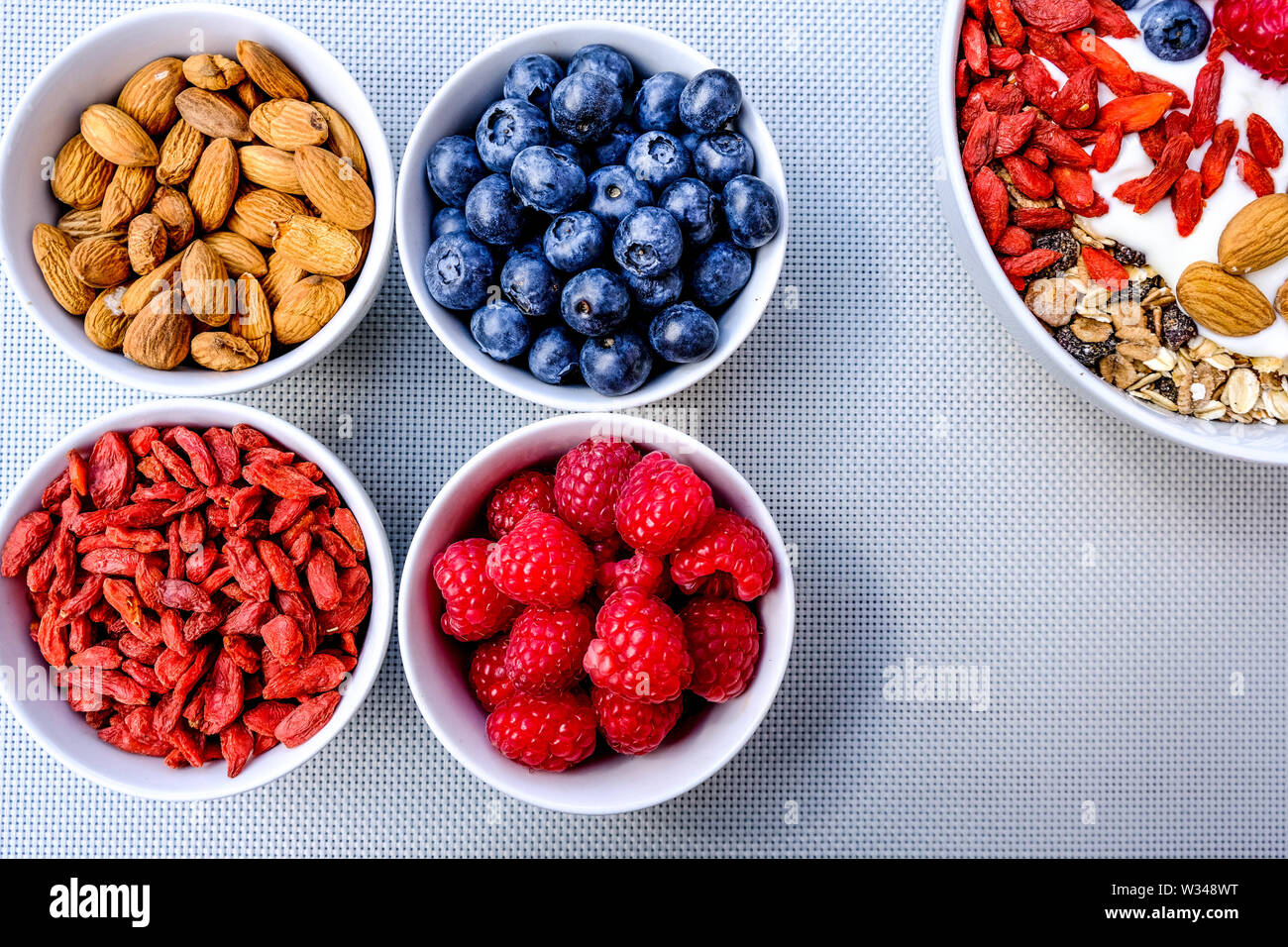 Una sana colazione vegetariana ciotola di muesli con frutta fresca i dadi e yogurt in bianco Bocce Foto Stock
