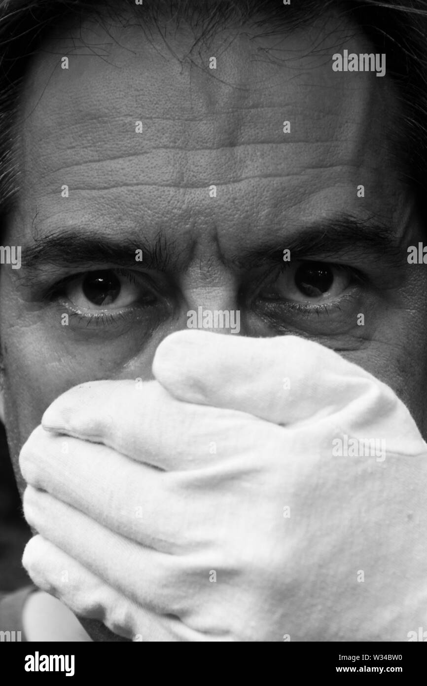 Il volto dell'uomo parzialmente coperto da un guanto bianco Foto Stock
