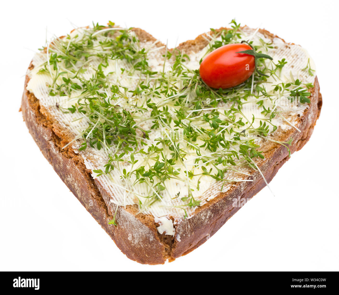 Un pane condito con burro, il crescione e un pomodoro a forma di cuore Foto Stock