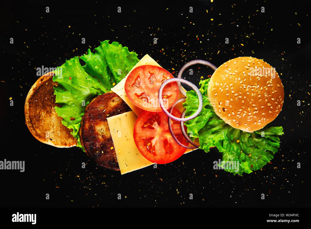 Flying ingredienti per un hamburger fatti in casa su uno sfondo nero. Non la dieta alimentare, alimenti dannosi per la salute. Foto Stock