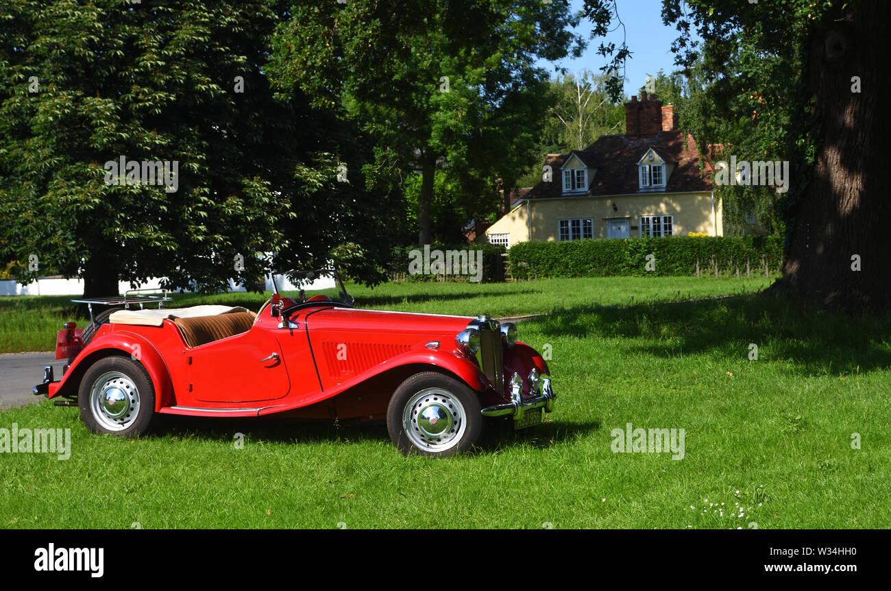 Rosso classico motore MG auto parcheggiate sul verde del villaggio. Foto Stock