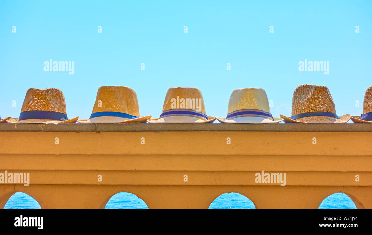 Uomo di paglia cappello da sole in una fila sulla ringhiera in mare a sud del resort Foto Stock