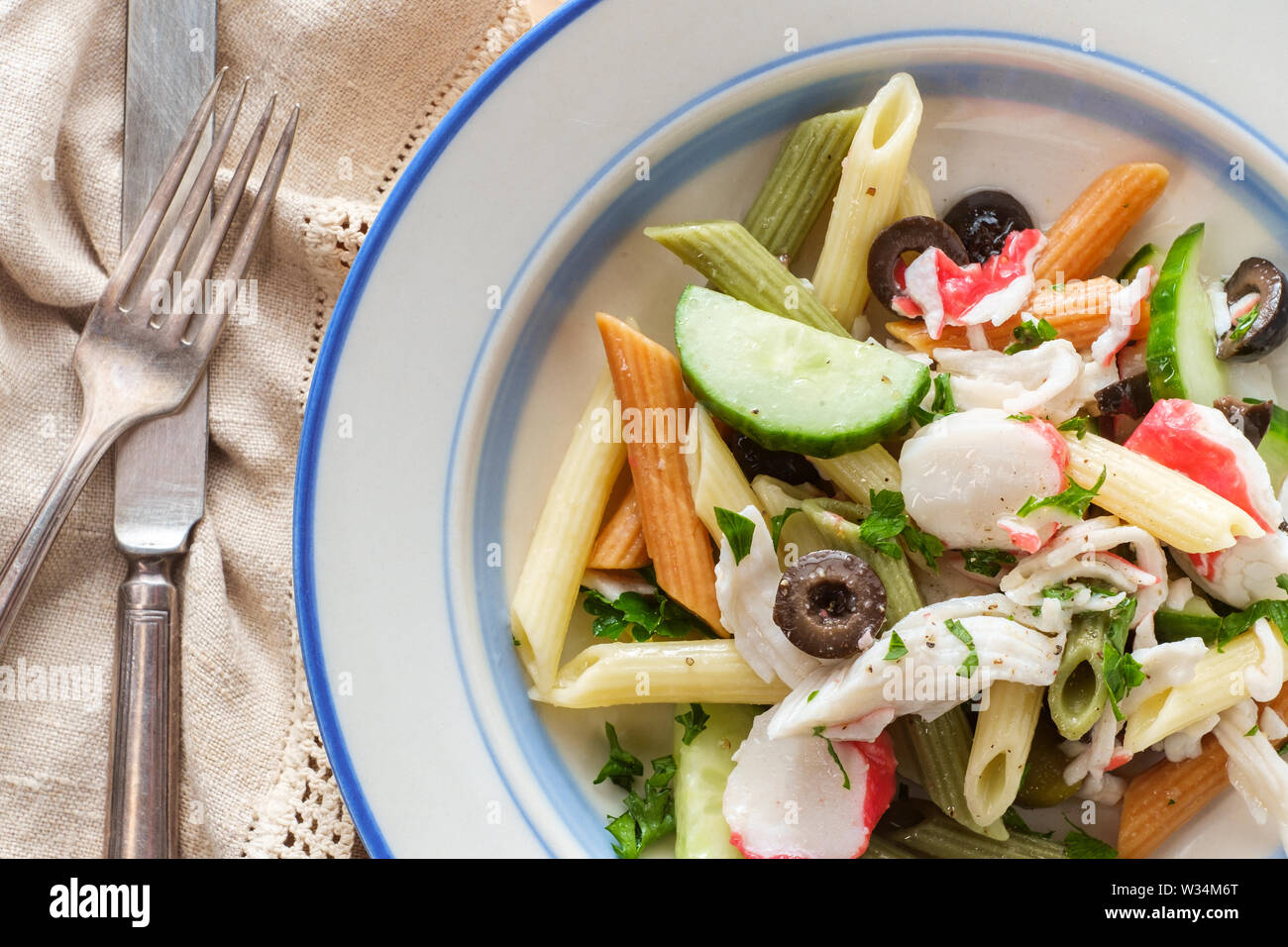 Frutti di mare insalata di pasta con polpa di granchio imitazione tricolore  penne olive e cetrioli Foto stock - Alamy