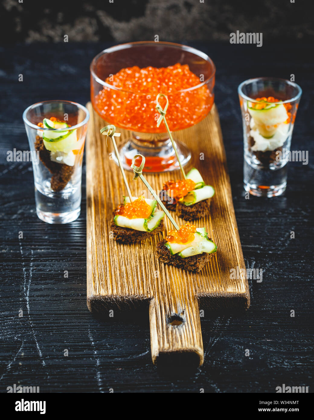 Deliziosi crostini con caviale rosso e porzionato spuntini con caviale e cetriolo in bicchieri. Foto Stock