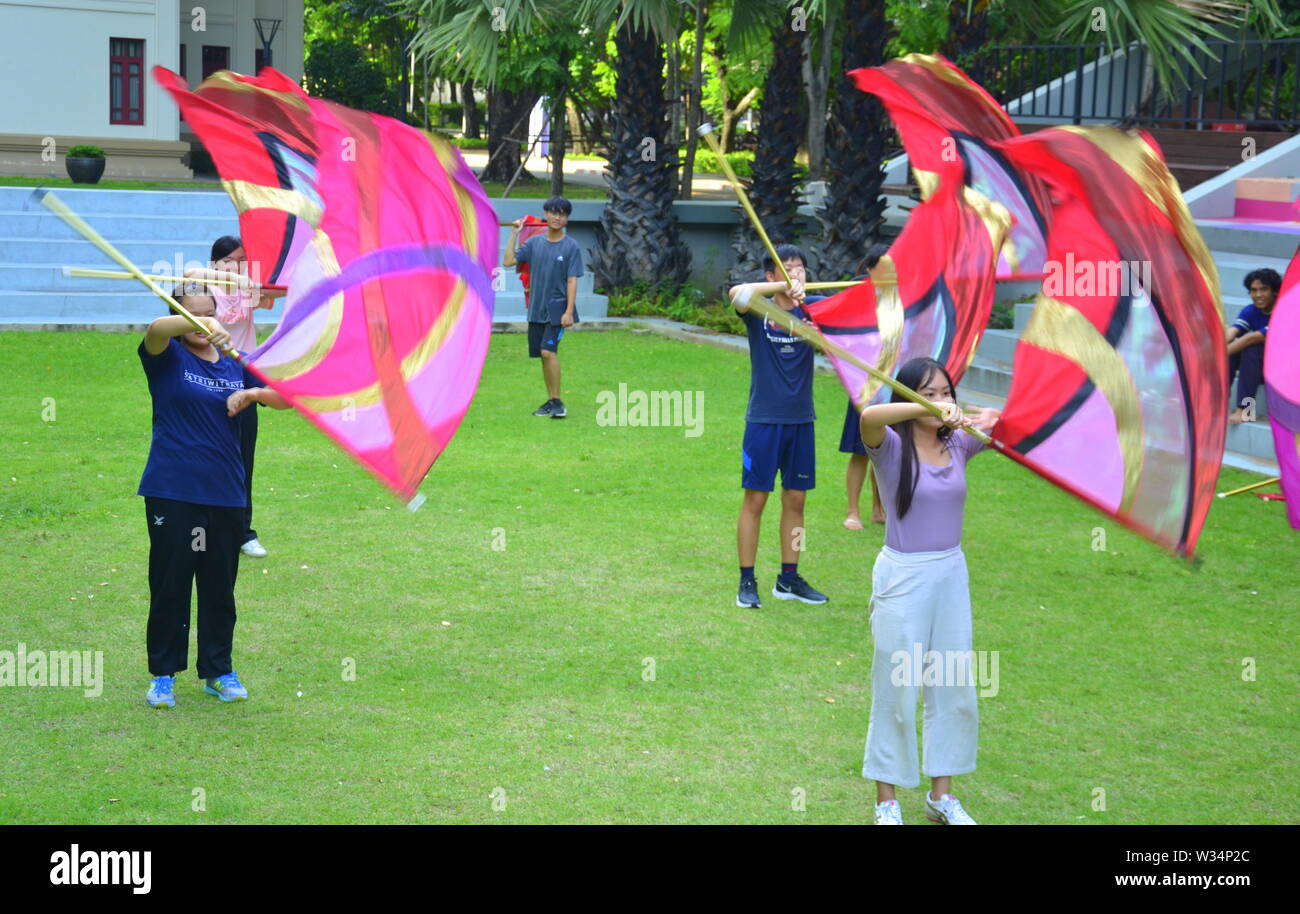 Giovani studenti in pratica la filatura di bandiera al di fuori sul prato all'università di Chulalongkorn nella zona centrale di Bangkok, Thailandia, Asia Foto Stock