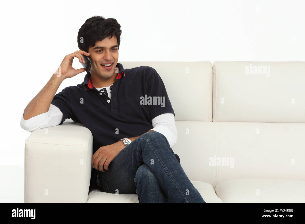Indian giovane uomo a parlare su un telefono mobile e sorridente Foto Stock