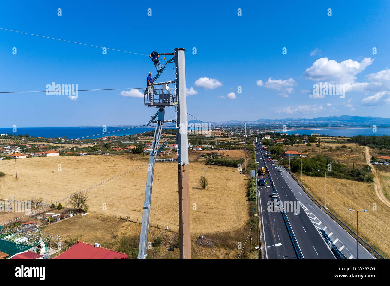 Calcidica, Grecia - Luglio 12, 2019: elettricisti sono arrampicata su poli elettrici da installare e riparare le linee di potenza dopo la violenta tempesta che ha colpito il t Foto Stock