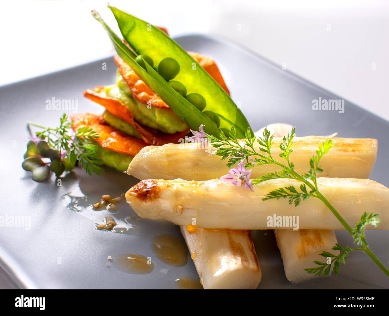 Asparagi bianchi freschi raccolti nel marchfeld austria, e cucinato come un piatto con la salsa e seet baccelli di piselli Foto Stock