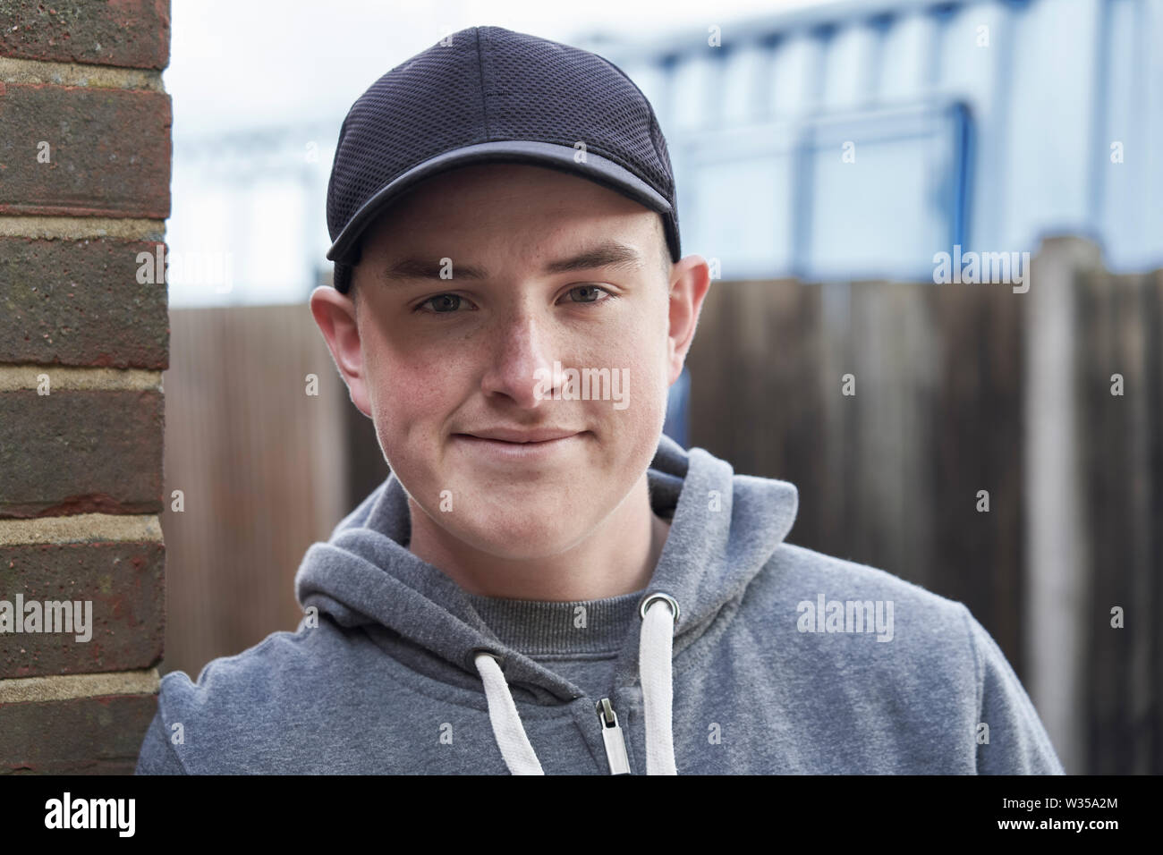 Ritratto di sorridere ragazzo adolescente appoggiata contro la parete nel contesto urbano Foto Stock