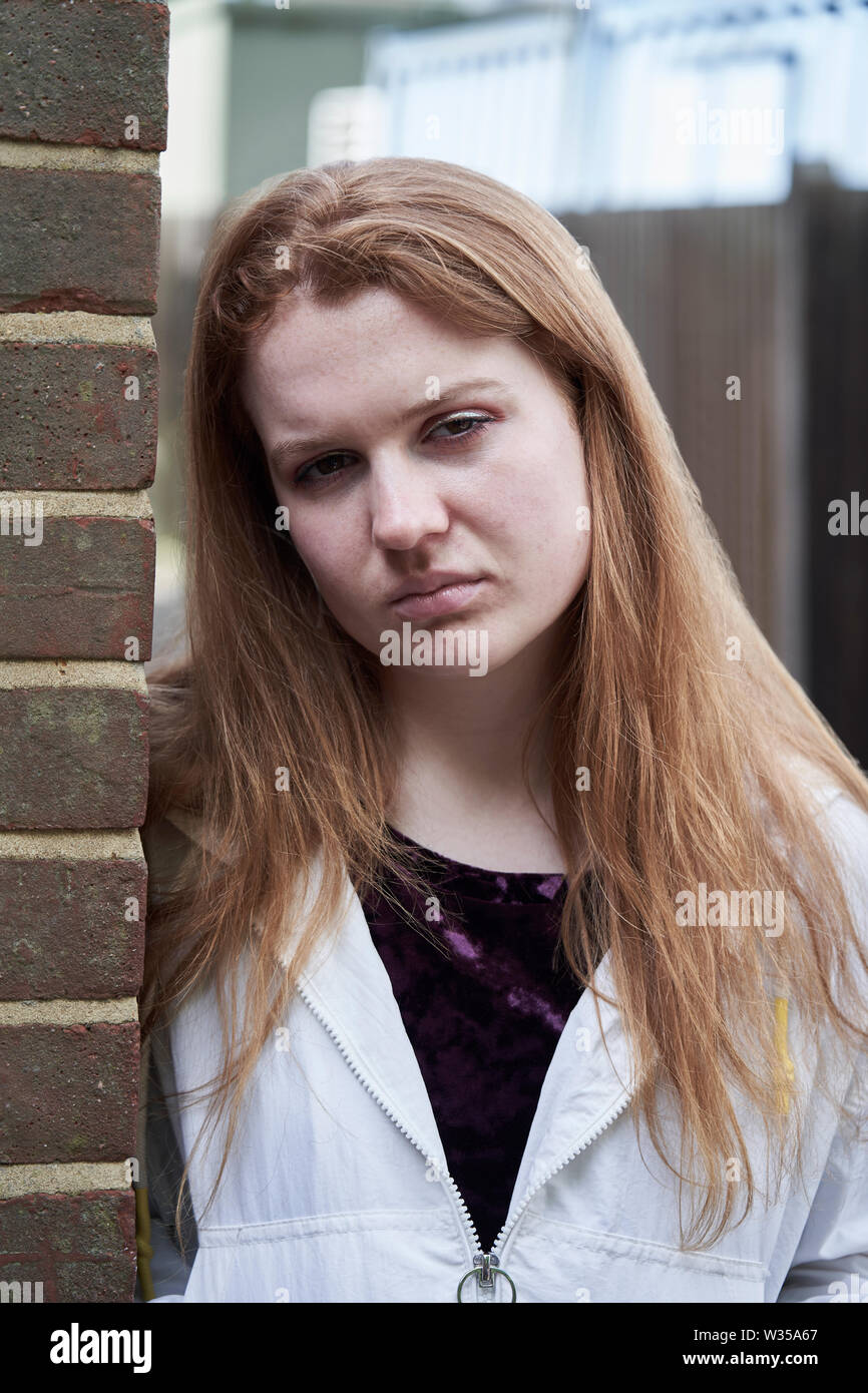 Ritratto di grave ragazza adolescente appoggiata contro la parete nel contesto urbano Foto Stock