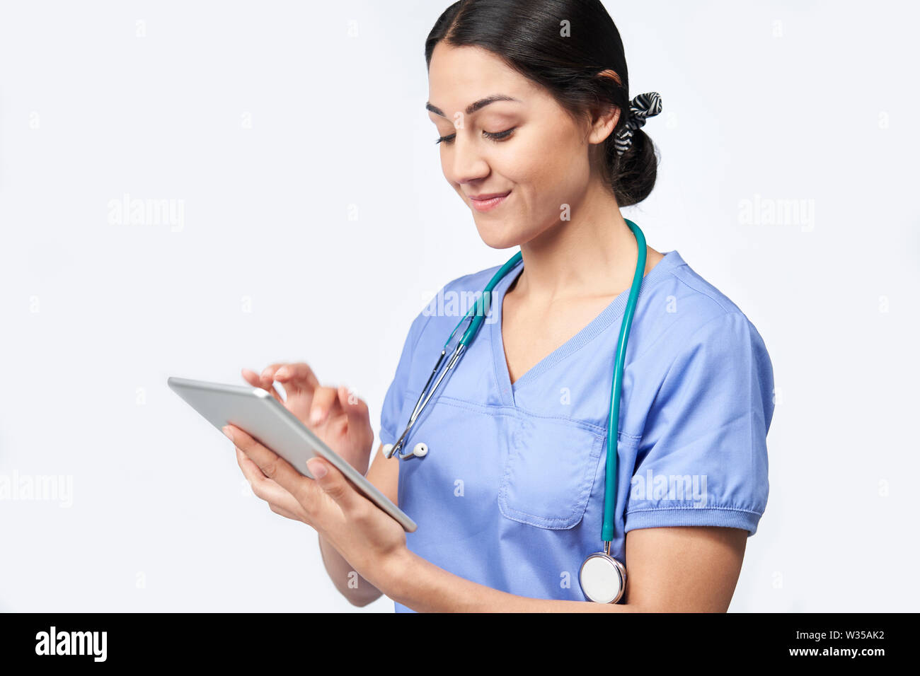 Studio shot di infermiera femmina indossando Scrubs utilizzando tavoletta digitale Foto Stock