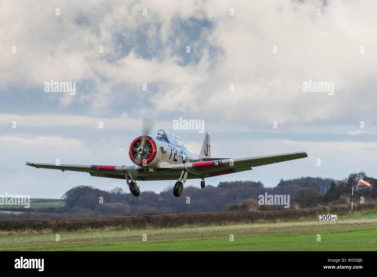 Harvard T6 Warbird avvicinando un'erba pista di atterraggio per aerei con carrello di atterraggio scendendo Foto Stock