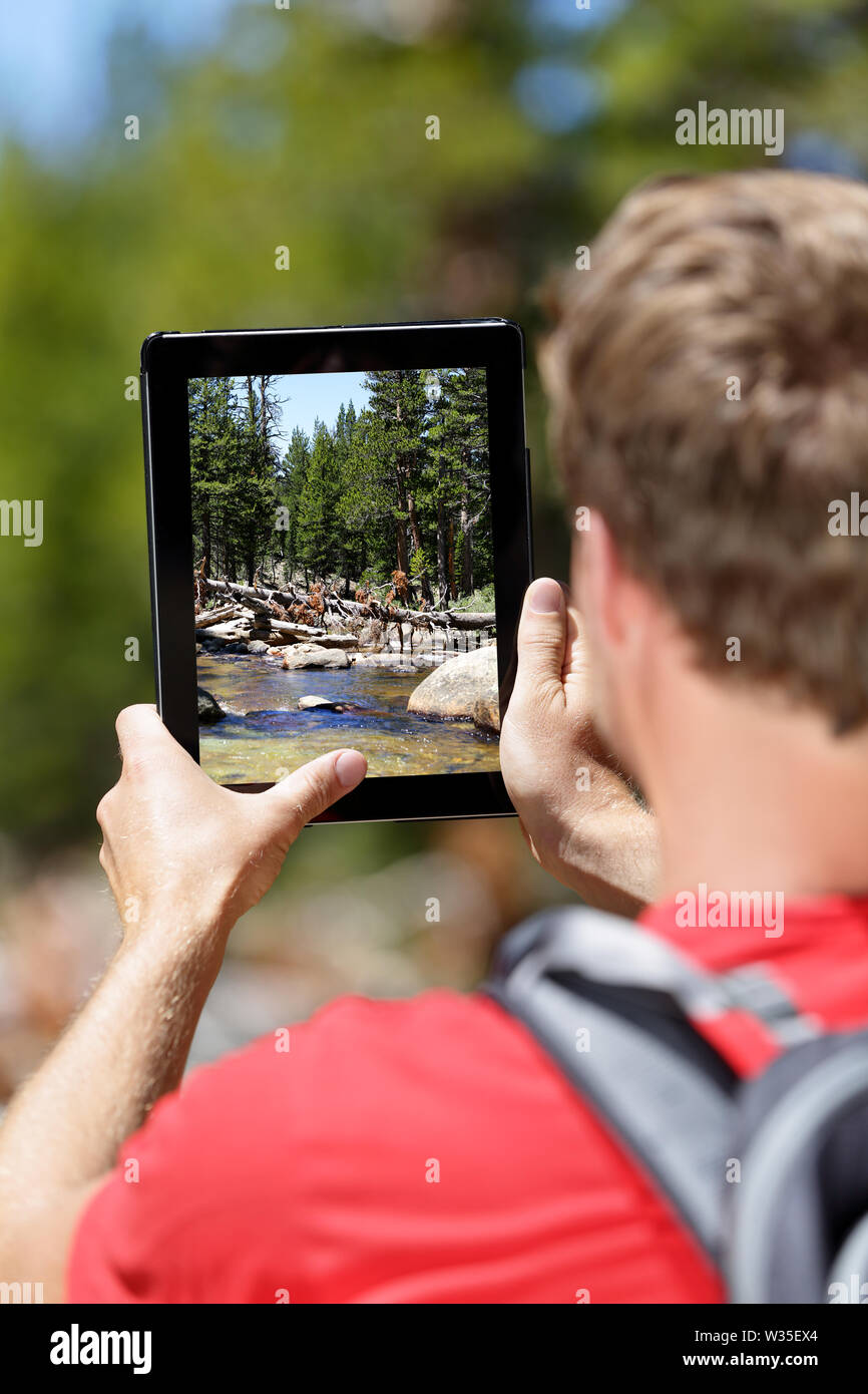 Escursionismo escursionista uomo a scattare foto di foresta sul digital computer tablet. I giovani adulti facendo fotografia mobile della natura nel Parco Nazionale di Yosemite in California, Stati Uniti d'America. Foto Stock