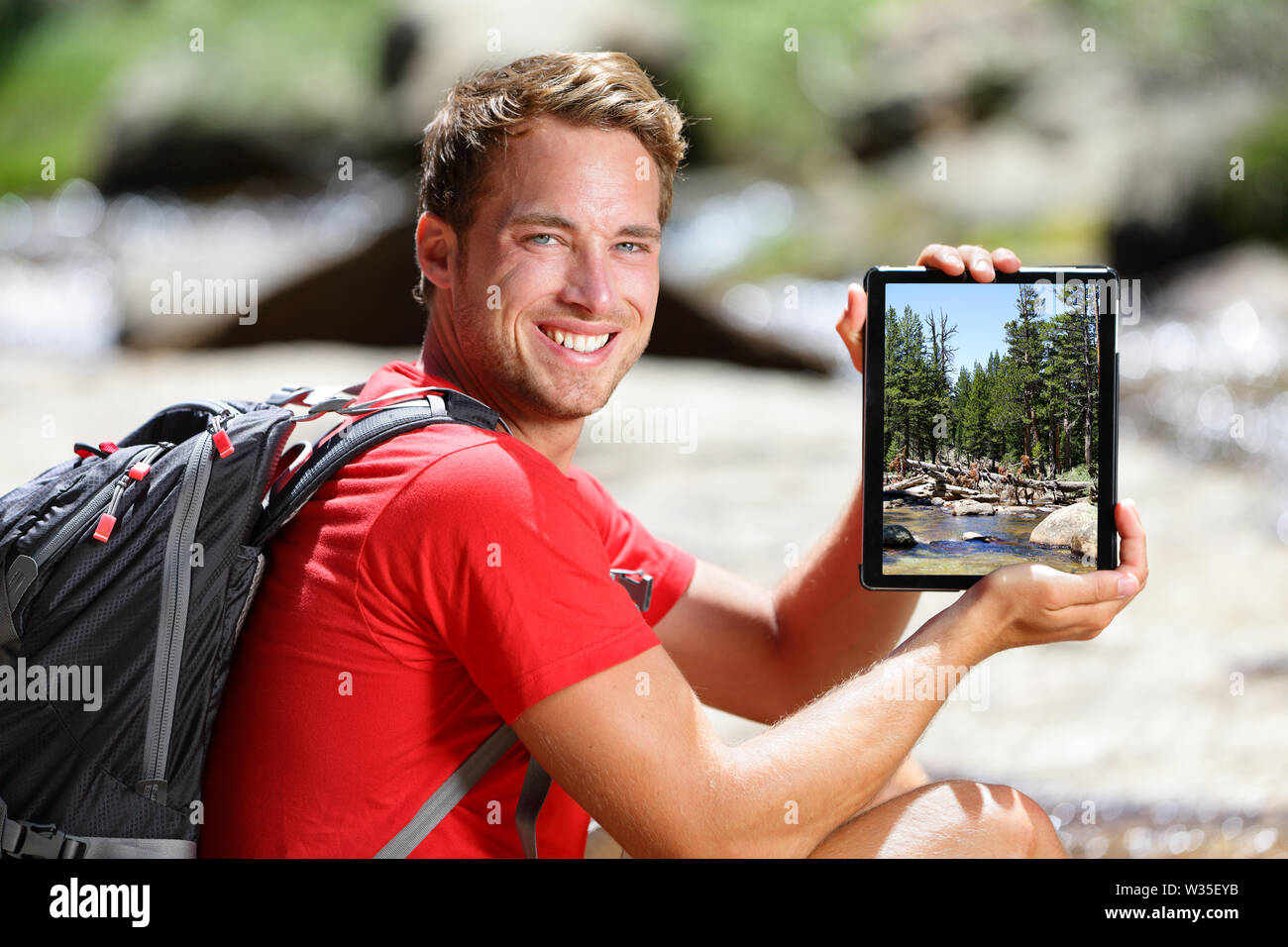 Escursionismo uomo che mostra la natura foresta immagine sul tablet. I giovani adulti a prendere foto con tavoletta digitale computer del paesaggio nel Parco Nazionale di Yosemite in California, Stati Uniti d'America. Foto Stock