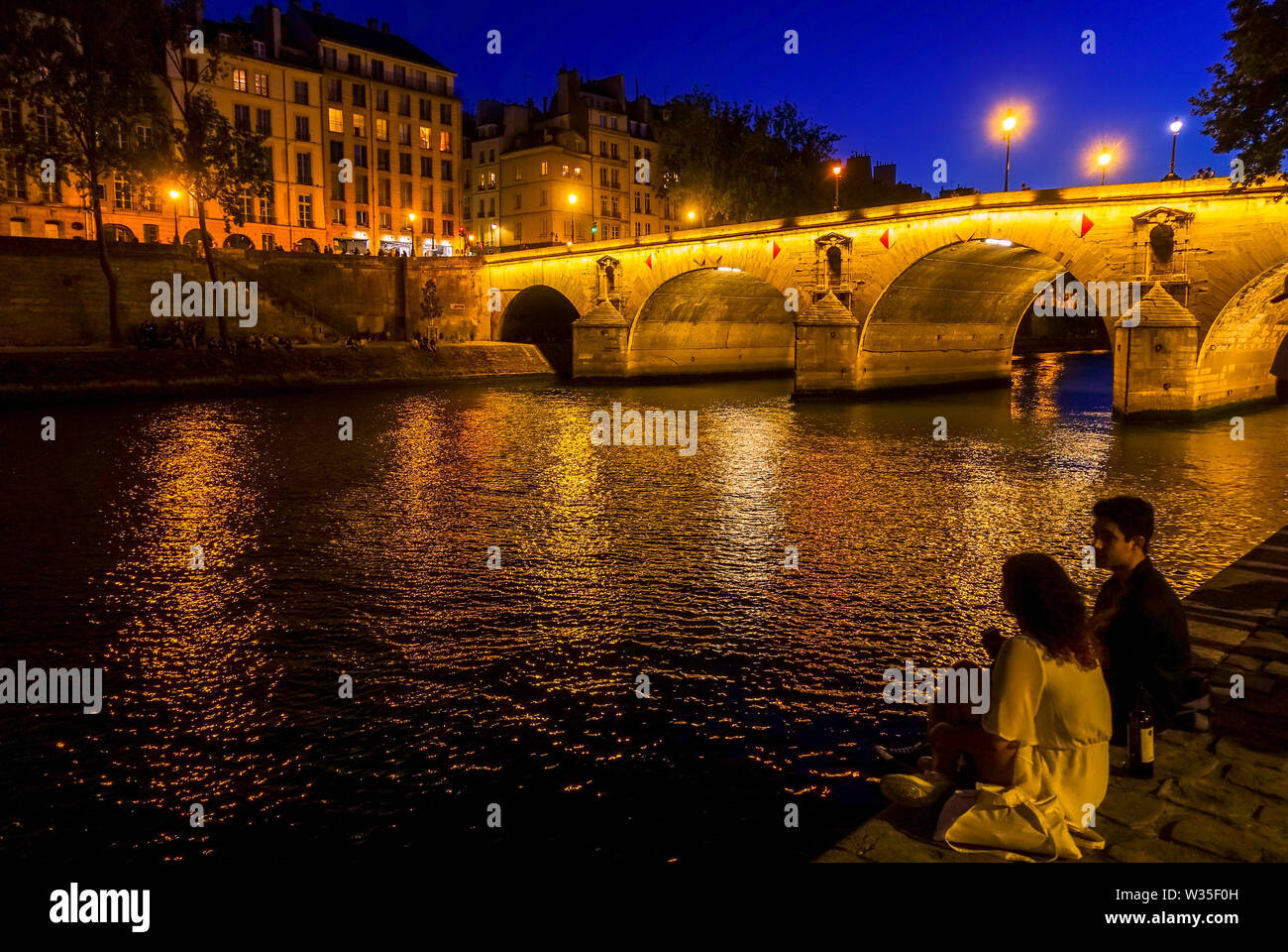 Coppia giovane a Pont Marie ponte illuminato di notte Ile Saint Louis, presso il fiume Senna, Parigi, Francia. Foto Stock