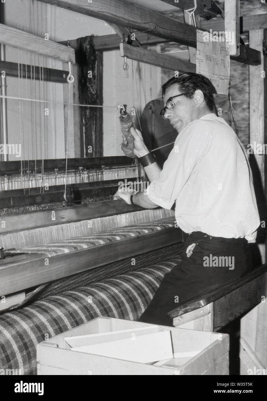 Anni '1960, storico, un uomo seduto, che usa un tradizionale telaio di tessitura, Scozia, Regno Unito. Questi telai erano interamente azionati da weaver, che utilizzava i pedali per spostare le filettature sui telai in legno. Foto Stock