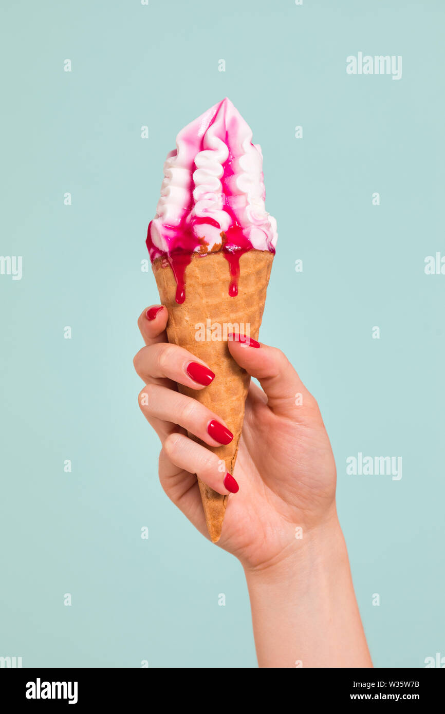 Donna che mantiene il gelato in un cono di cialde su uno sfondo colorato. Foto Stock