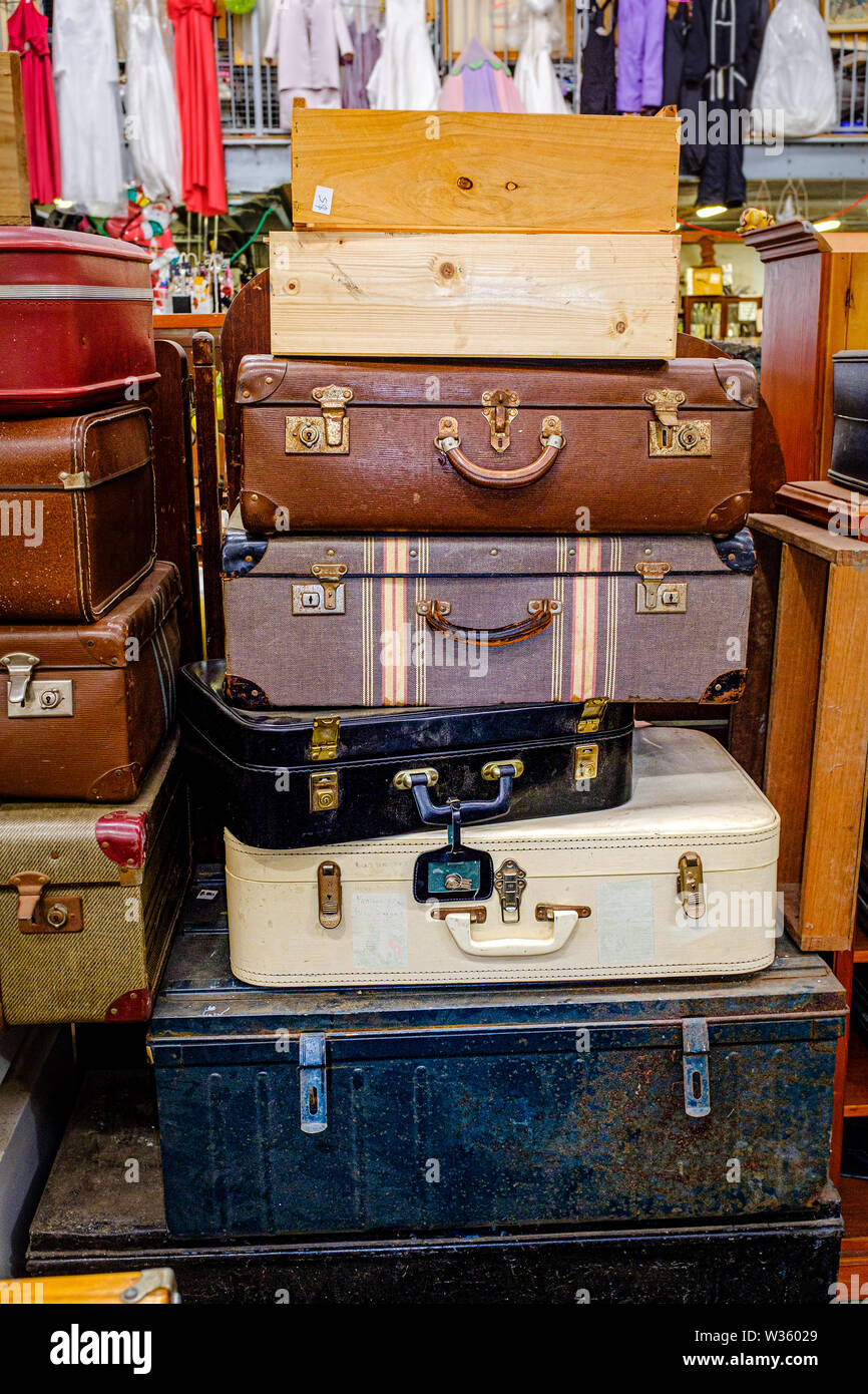 Una pila di vecchi e valigie vintage, vaporizzatore trunk e scatole di legno sul display per vendere a carità centro di riciclaggio Foto Stock