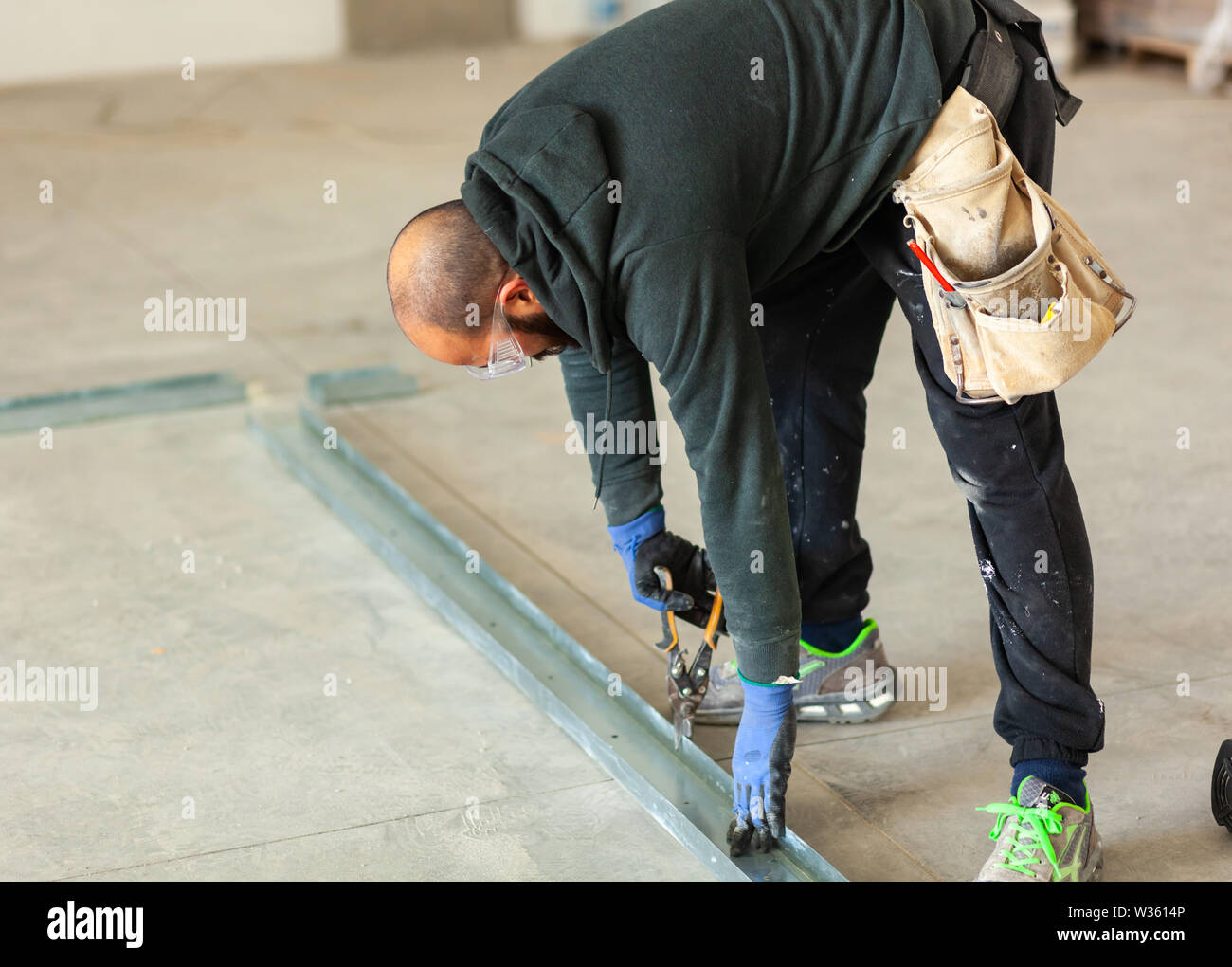 Lavoratore a lavorare per la costruzione di una parete di cartongesso. Foto Stock