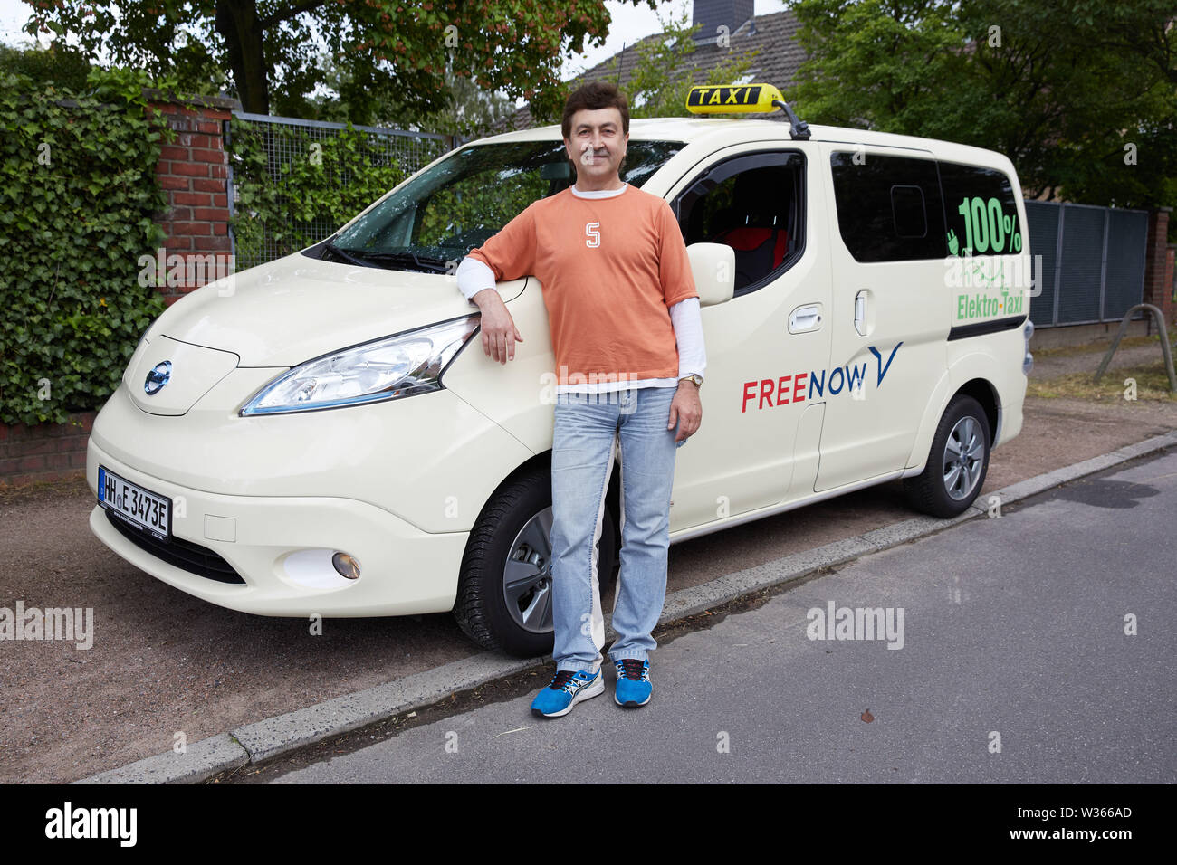 Amburgo, Germania. 12 Luglio, 2019. Kostantin Khmelevskyy, taxi driver, sorge accanto alla sua Nissan e-NV 200 Evalia con l'iscrizione: "100% taxi elettrico". Il taxi Khmelevskyy imprenditore è il solo proprietario di una completamente taxi elettrico ad Amburgo. Credito: Georg Wendt/dpa/Alamy Live News Foto Stock