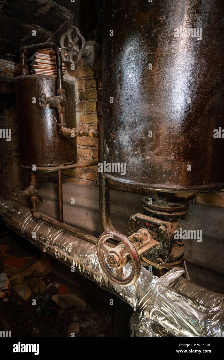 Rusty sala caldaia tubi. Metallo vecchia caldaia di riscaldamento di generazione e di consegnarla a casa tramite pipeline. Acqua calda o gas viene fornito con questo Foto Stock