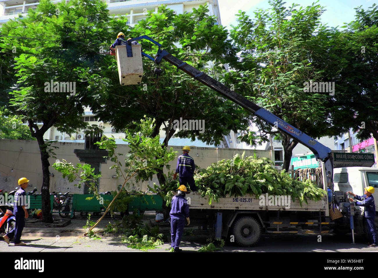 Ho Chi Minh city, Vietnamita lavoratore lavoro sul braccio di sollevamento per tagliare il ramo di albero per la sicurezza nella stagione delle piogge, autogru su strada per un gruppo di persone che lavorano Foto Stock