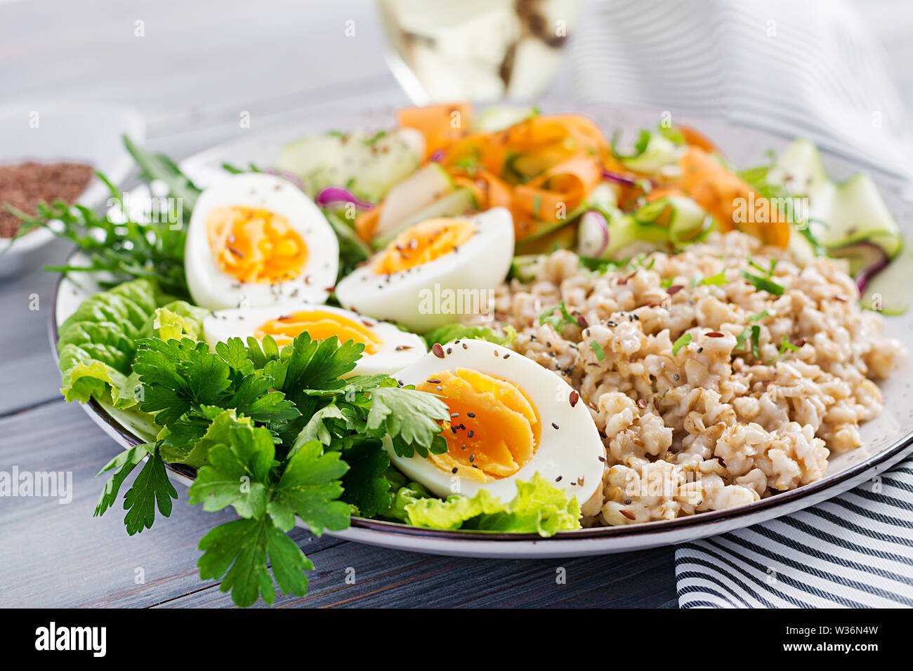 La colazione ciotola con i fiocchi d'avena, zucchine, lattuga, carota e uova sode. Insalata fresca. Cibo sano. Vegetariano ciotola di buddha. Foto Stock