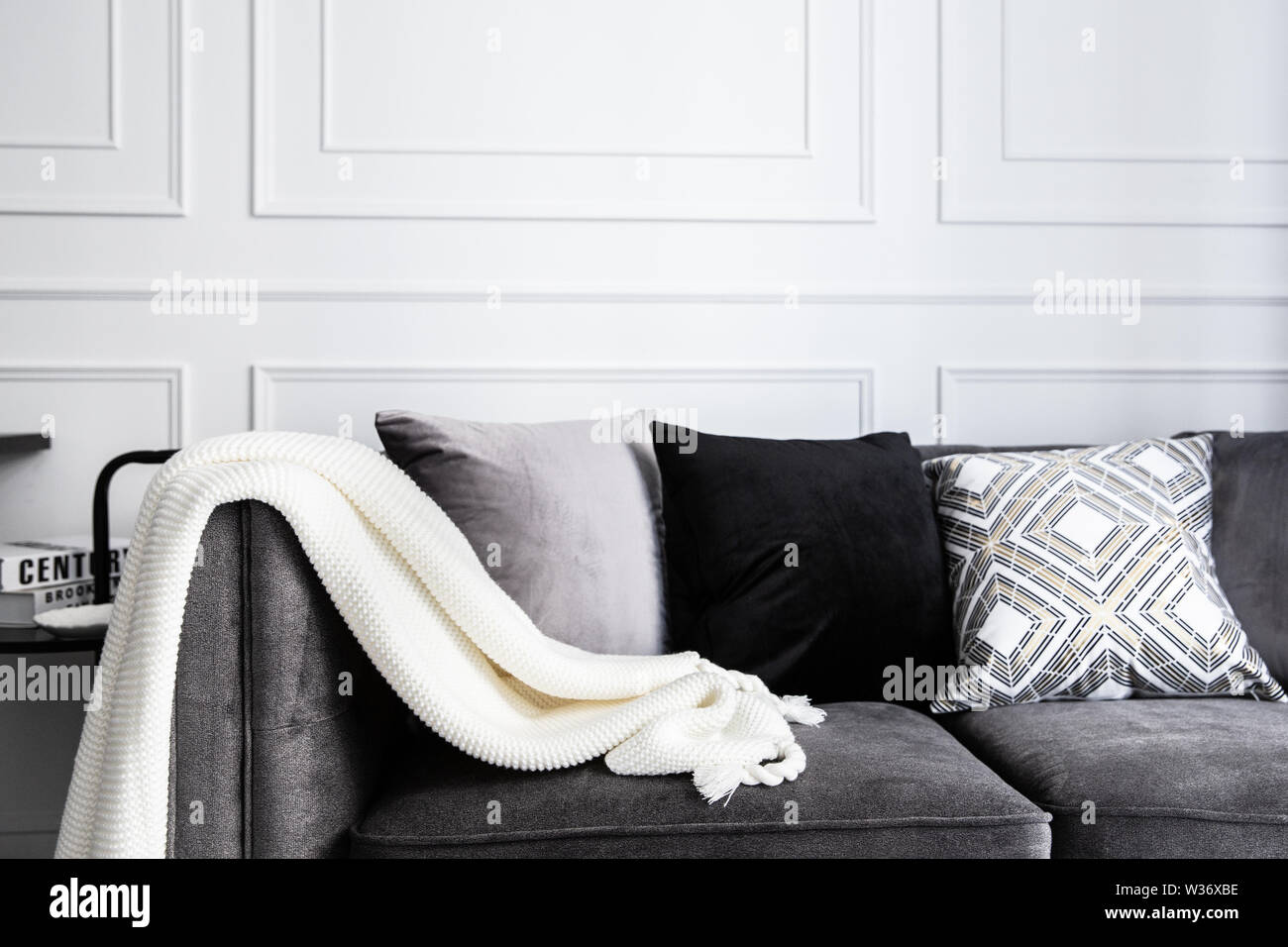 Soggiorno interno con con il grigio fablic divano, comodi cuscini, plaid e maglia whithe coperta. Decorazione moderna room interior design. Foto Stock