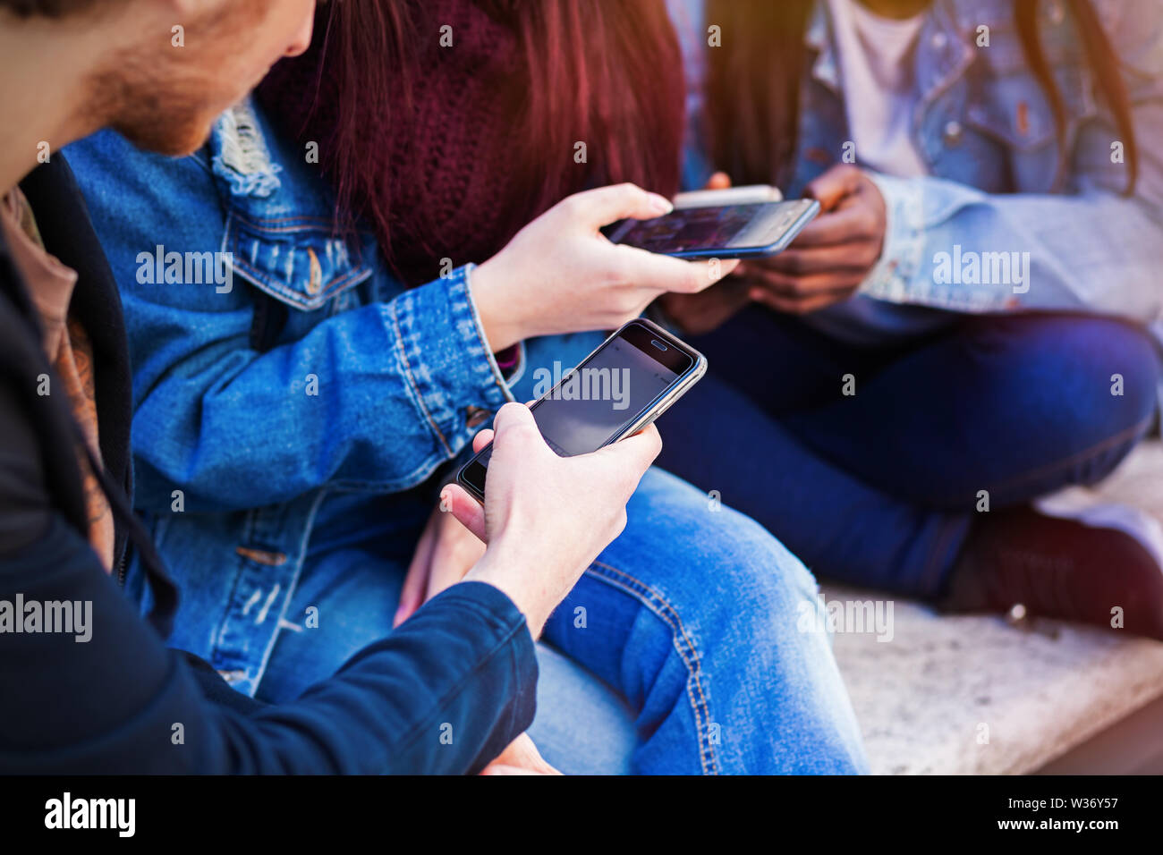 Tre giovani utilizzando il telefono cellulare. Concetto di amicizia in tempi moderni. Foto Stock