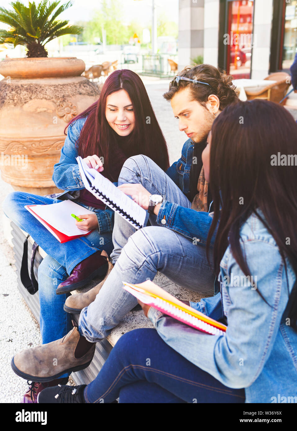 Tre studenti su un banco all'esterno. Interracial e concetto di amicizia. Foto Stock