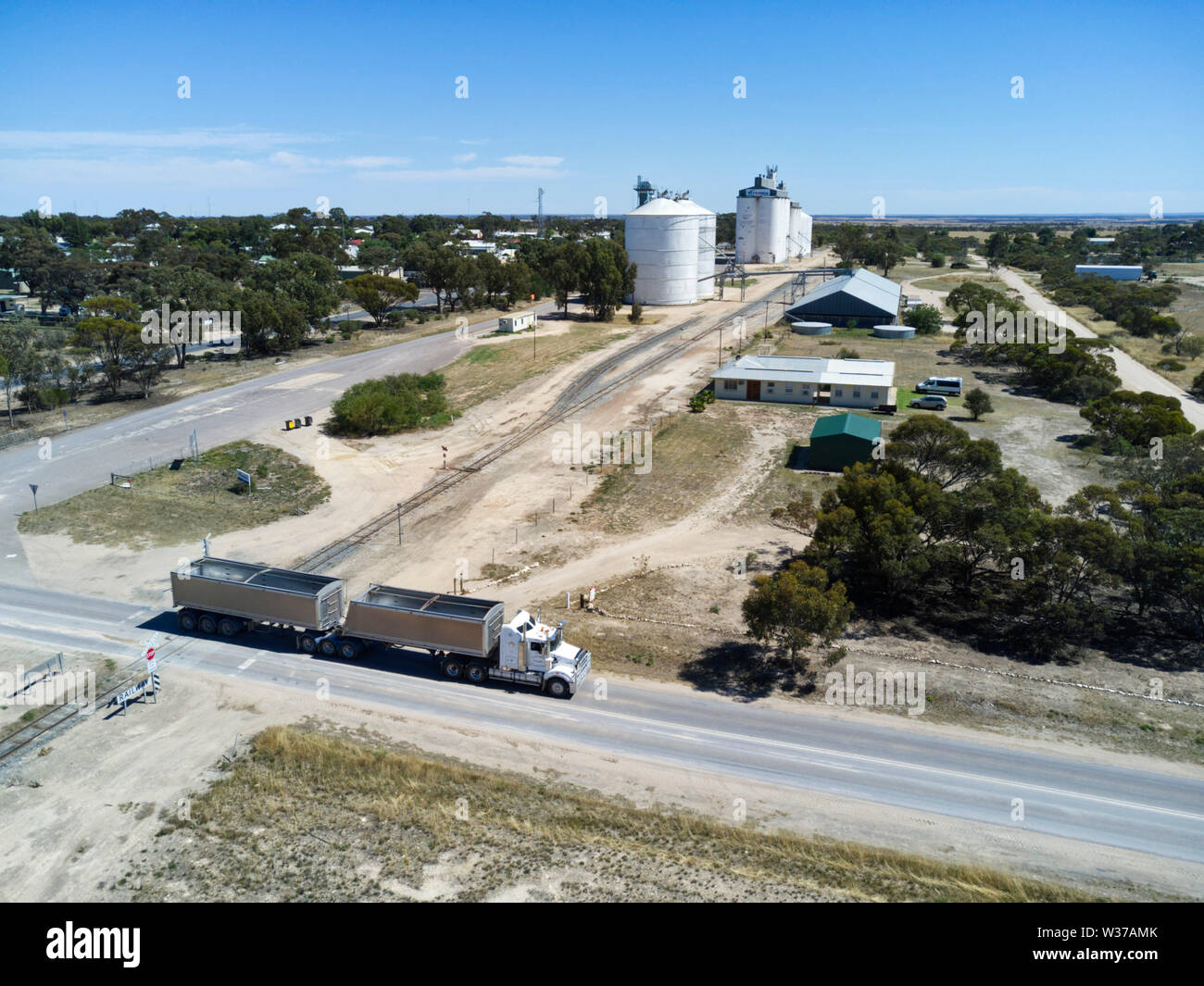 Antenna di roadtrain fermandosi ad incrocio ferroviario con il silo di grano di bloccaggio della penisola di Eyre South Australia in background Foto Stock