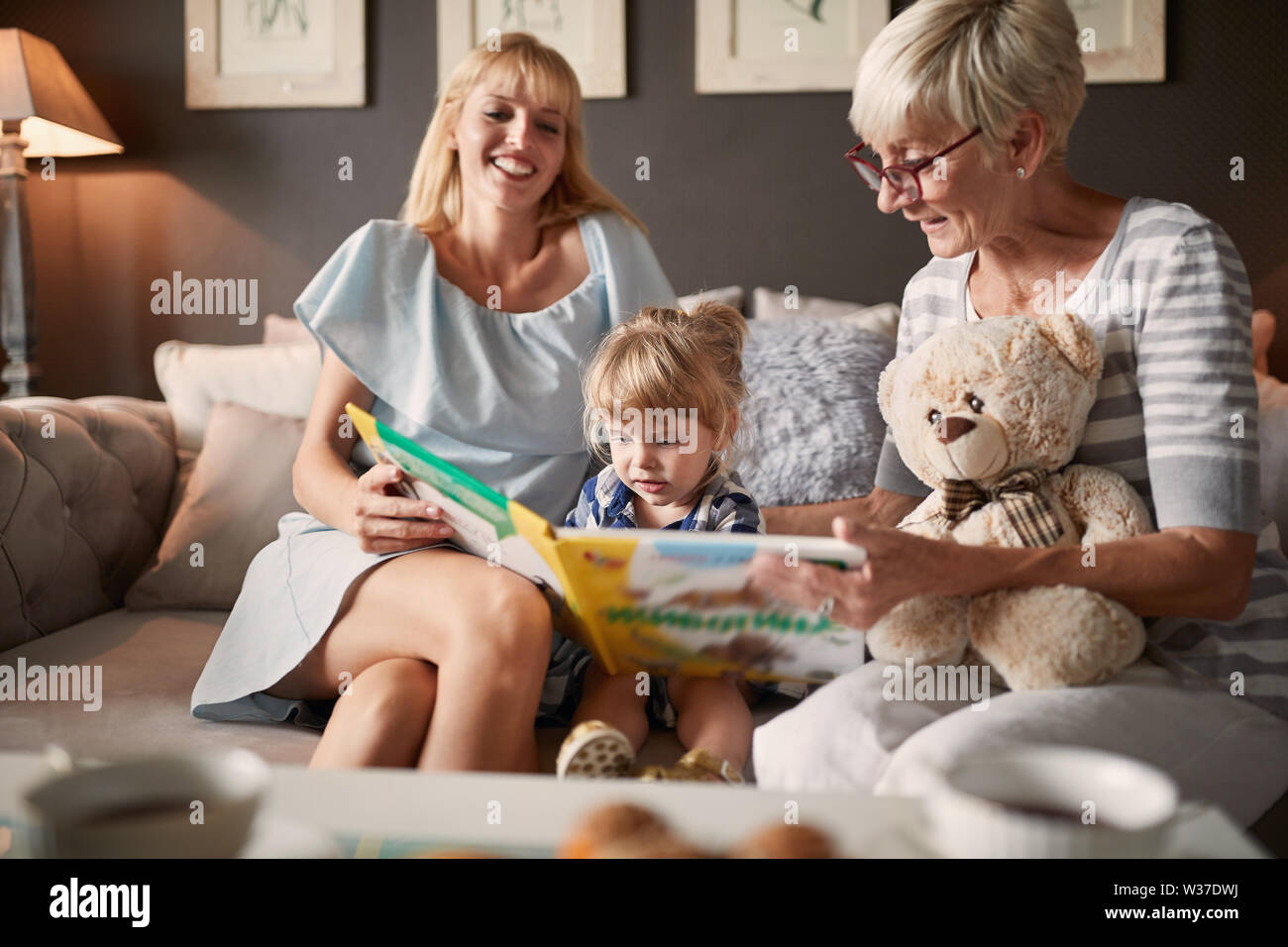 Bambino con sua madre e nonna cercando picture book Foto Stock