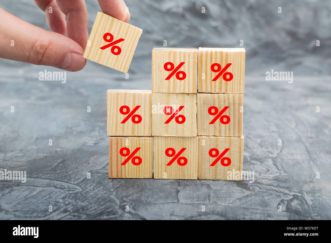 Mettendo mano cubo di legno crescente di blocco sulla parte superiore con icona simbolo di percentuale verso l'alto. Tasso d'interesse finanziario e tassi ipotecari concept Foto Stock