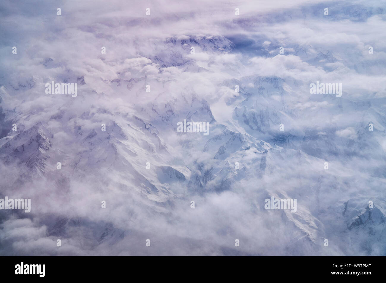 Luftbild der Alpen unter einer dichten milchigen Wolkendecke ragen die Gipfel der Gebirge mit Eis und Schnee bedeckten Bergen hervor. Foto Stock