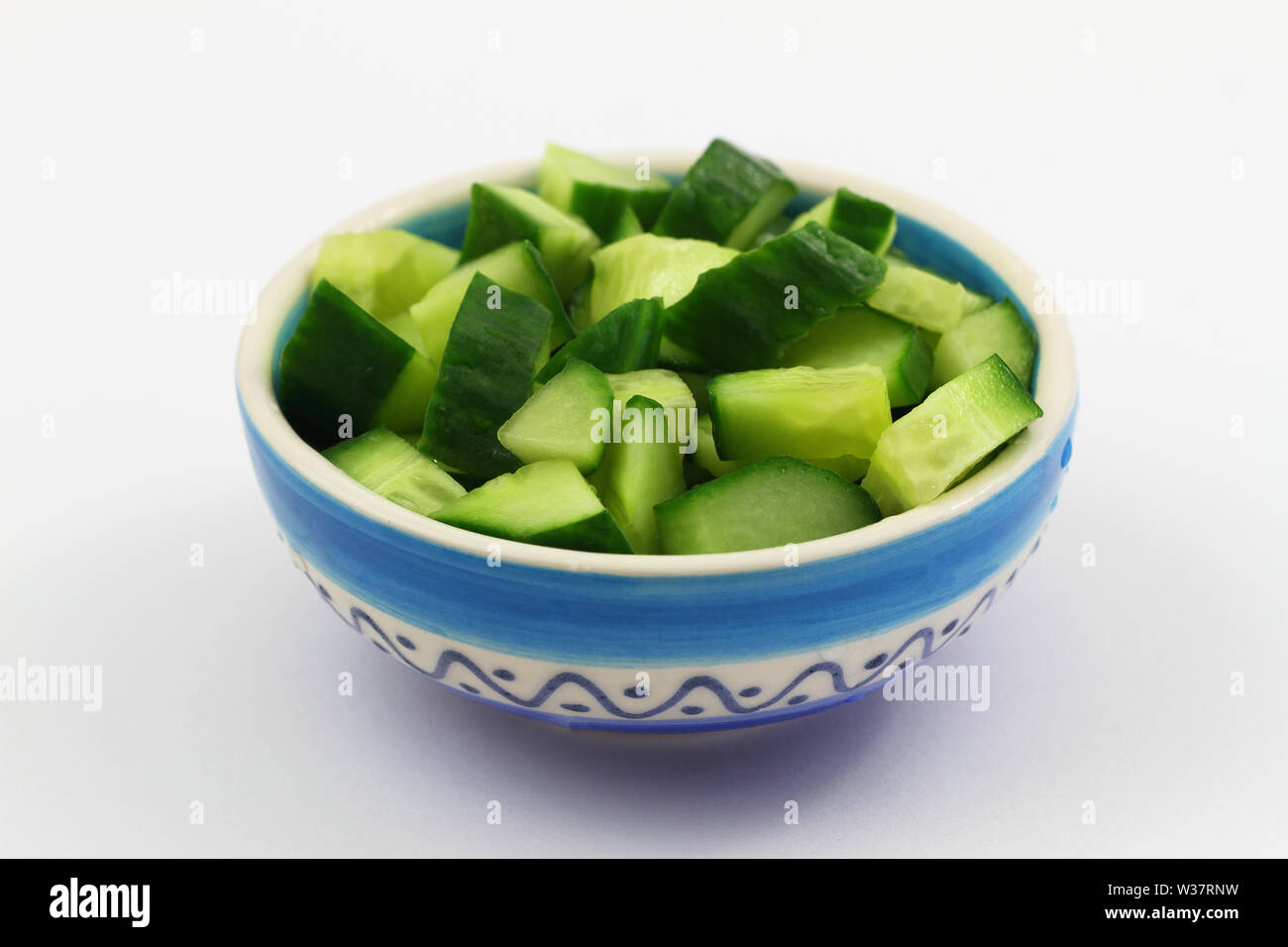 Fresco di cubetti di cetriolo in porcellana ciotola sulla superficie bianca Foto Stock