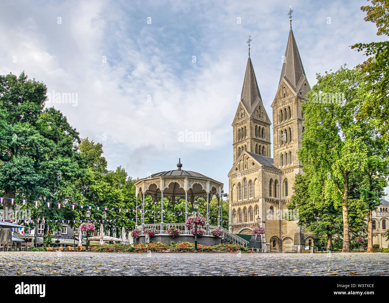 Roermond, Paesi Bassi, luglio 12, 2019: a basso angolo di vista del centro di Munster quadrato con palco per spettacoli, alberi e chiesa Foto Stock