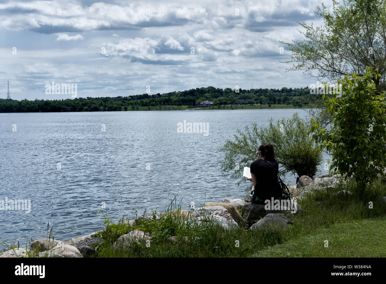Canada Ontario Barrie a giugno 2019, pausa pranzo nel parco, una donna è la lettura Foto Stock