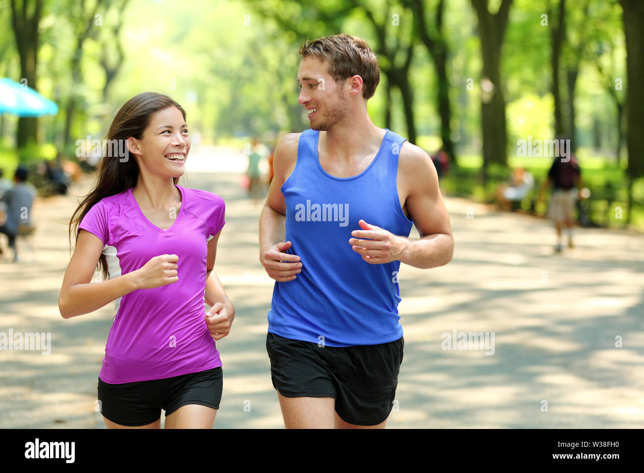 Esecuzione di giovane formazione nel Central Park di New York City (NYC). Felice corridori parlare insieme durante la corsa sul famoso Mall percorso a piedi sotto gli alberi in Manhattan, urban fitness. Foto Stock