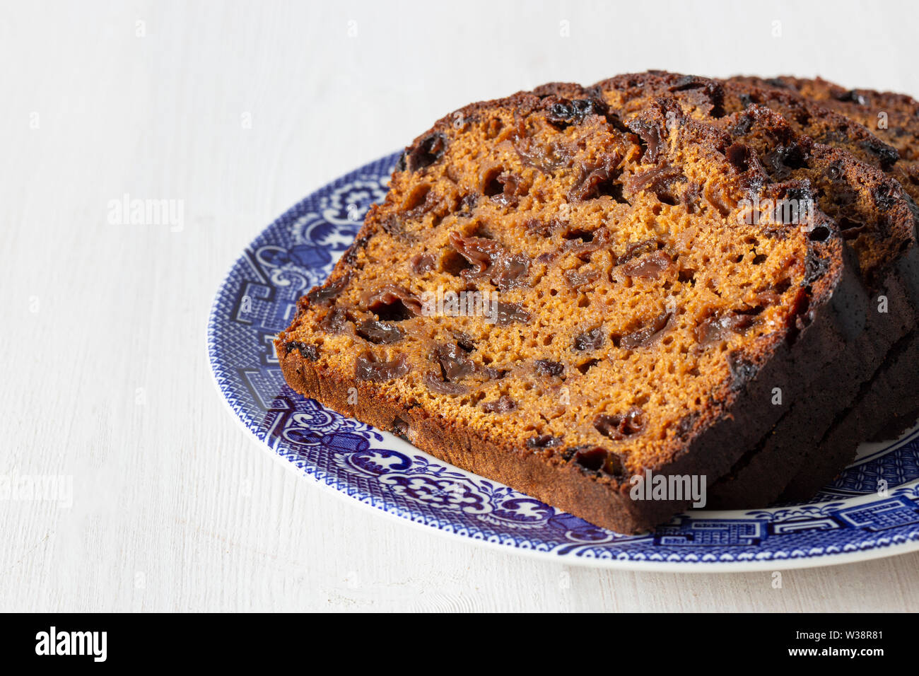 Pane di frutta a fette di torta su un decorate in blu e bianco piastra. Su un bianco sullo sfondo di legno Foto Stock
