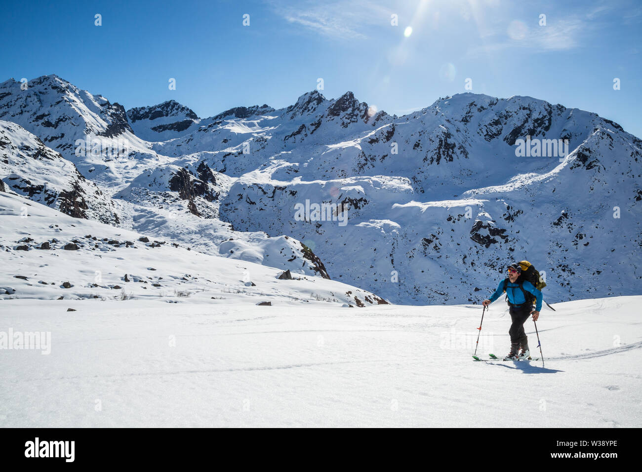 Backcountry rider escursionismo in salita su una luminosa giornata di sole in Alaskan backcountry. Lo sci primaverile in Talkeetna montagne. Foto Stock