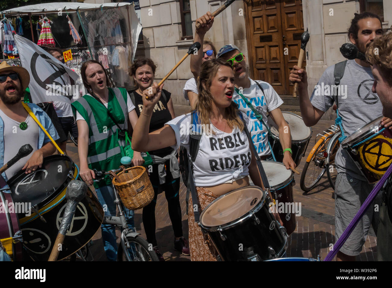 Londra, Regno Unito. 13 luglio 2019. La Ribellione di estinzione marzo da Hackney Downs a campi di Londra attraverso il centro di Hackney come promemoria dell'urgente necessità di agire per evitare di estinzione globale. Prima del marzo vi è stata una performance di danza e meditazione sui prossimi catastrofe climatica. Dietro il banner principale Dan chiave la band ha suonato per un tradizionale New Orleans funerali e fu seguita da scheletri giganti raffiguranti animali già estinte o sotto minaccia, una bara, le api giganti, persone con bandiere e una banda di samba. Peter Marshall / Alamy Live News Foto Stock