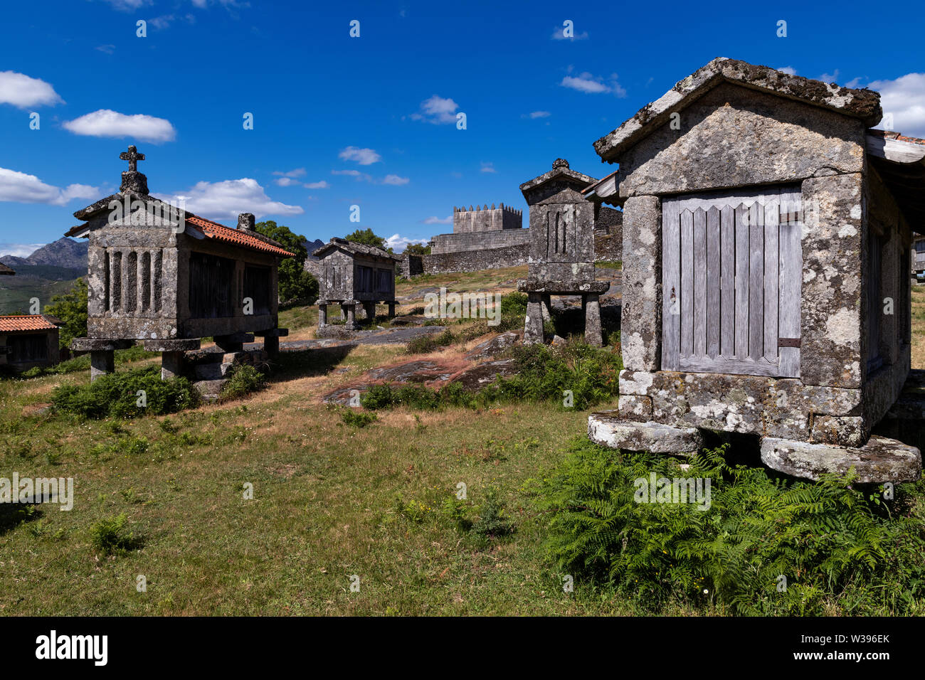 Vista dei granai (espigueiros) e castello medievale nel villaggio storico di Lindoso, Portogallo. Foto Stock