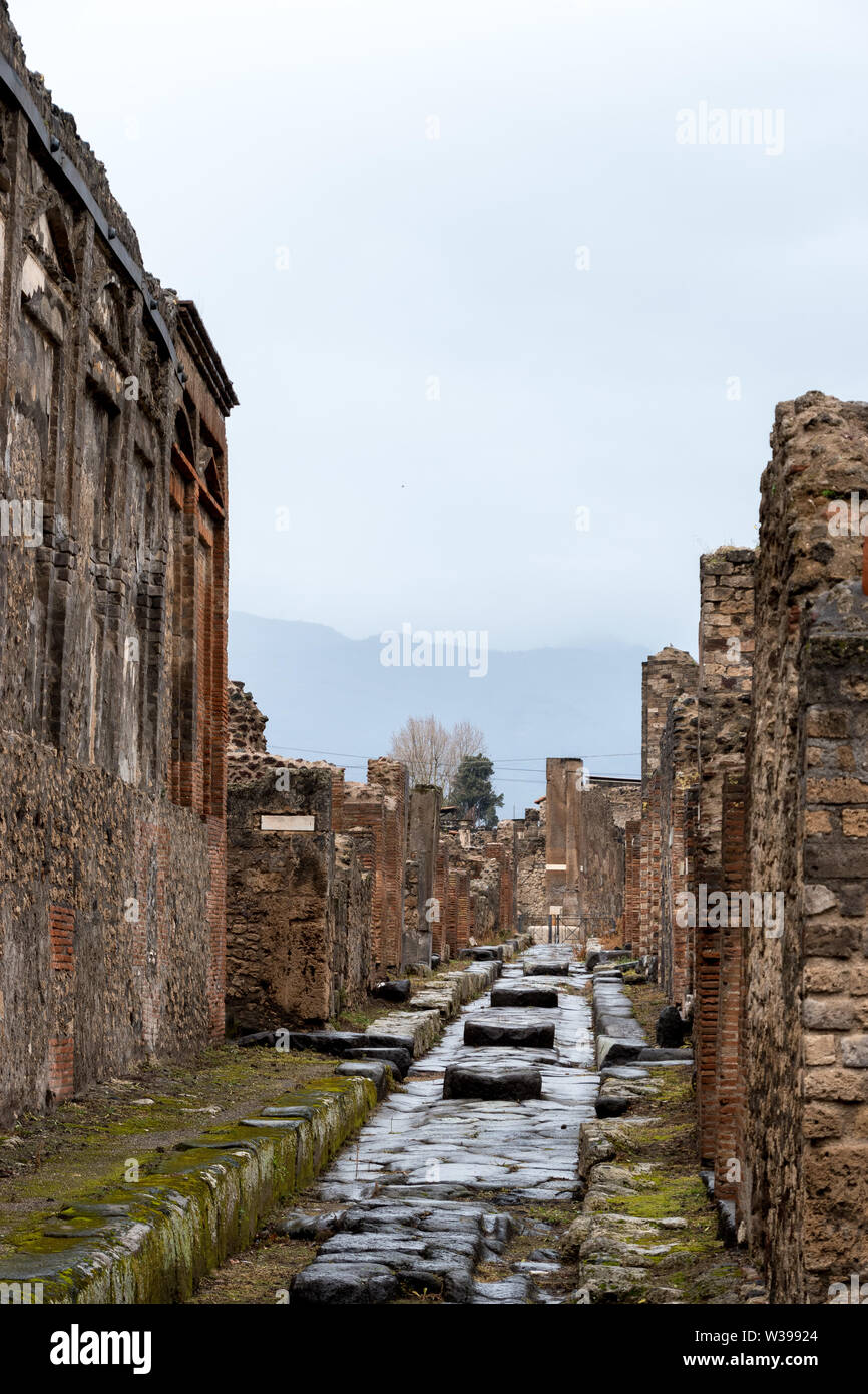 Un antica strada romana con ruota di carrello di solchi e una diga di Pompei, Italia Foto Stock