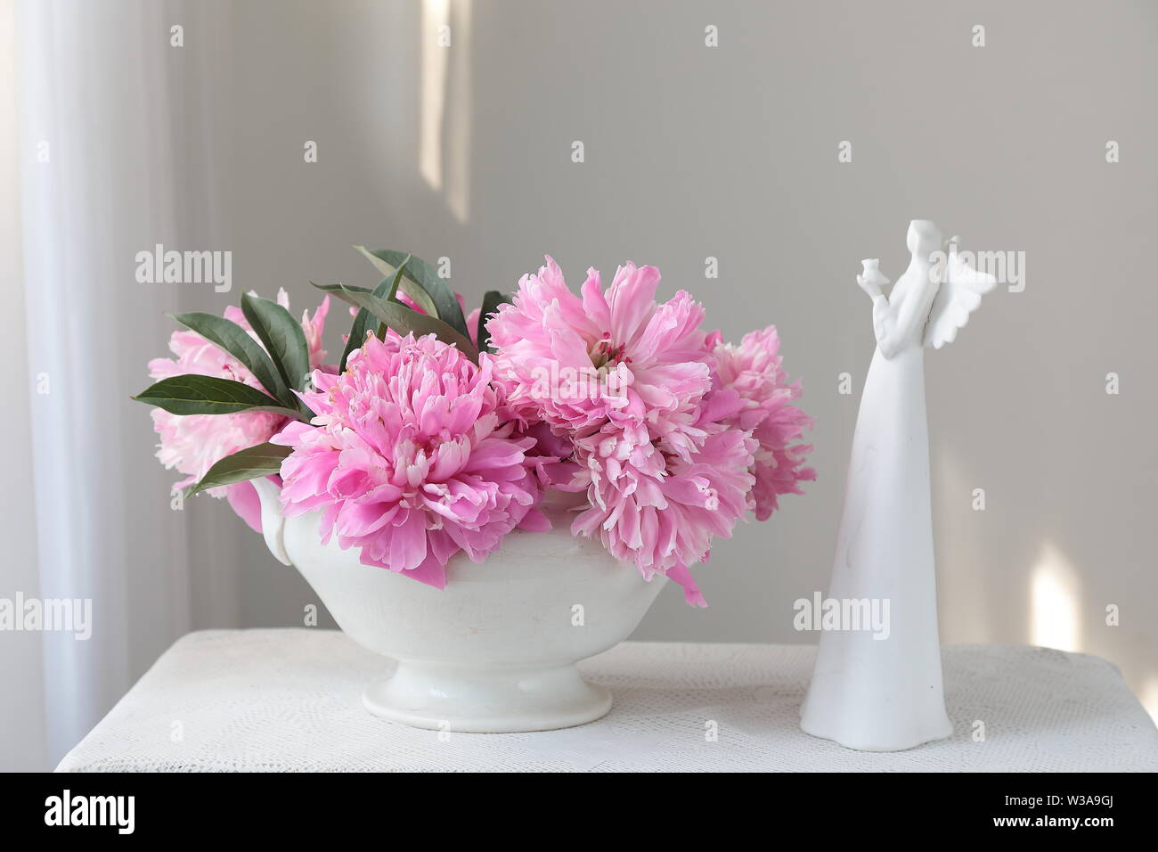 Rosa peonia fiori in un vaso bianco su un tavolo bianco. Sfondo bianco. Ancora in vita. Luce luce mattutina in interno bianco. Foto Stock