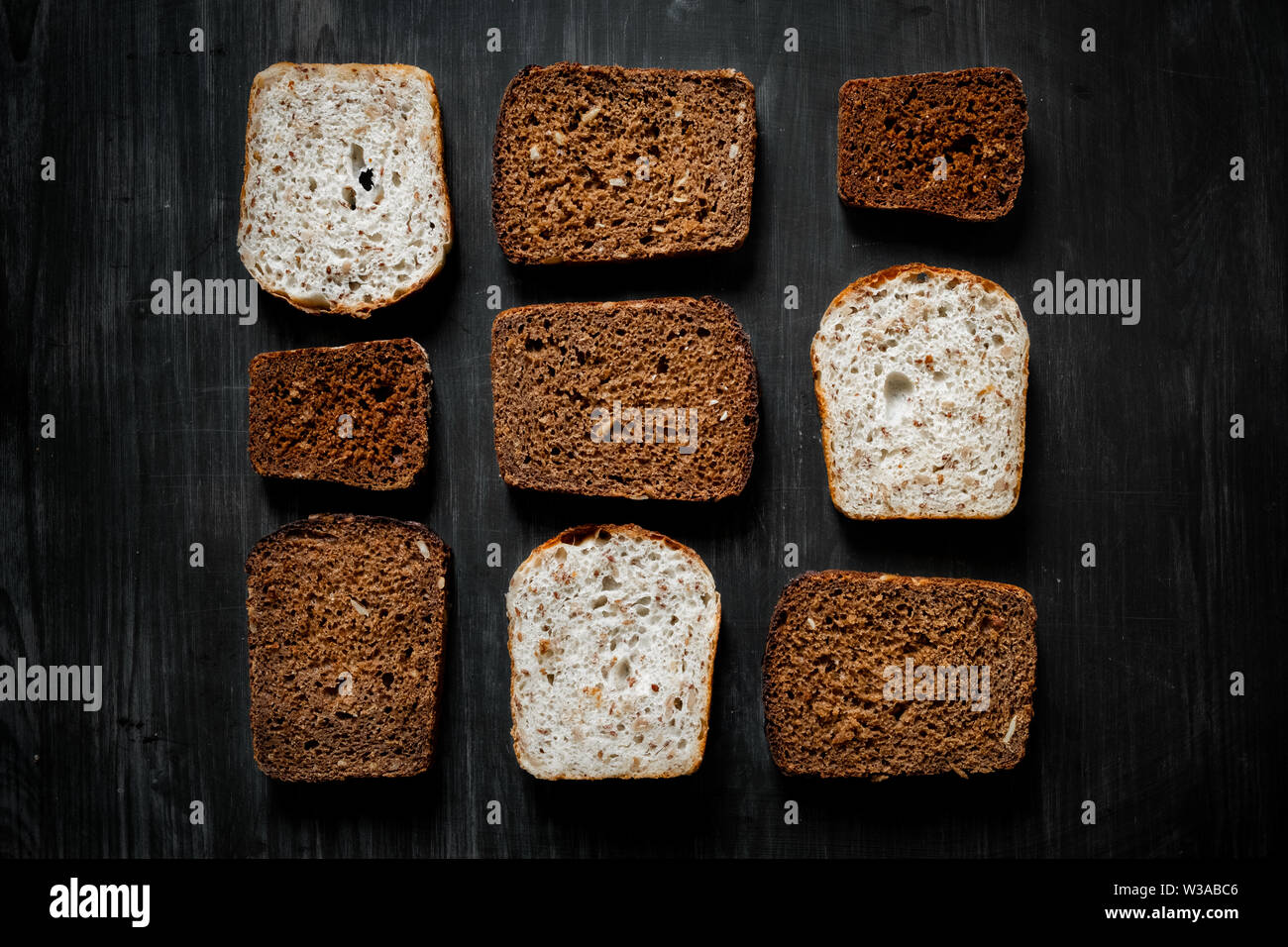 Modello di pane integrale le fette su legno scuro dello sfondo. Vista dall'alto di diversi tipi di pane, basso-chiave immagine Foto Stock