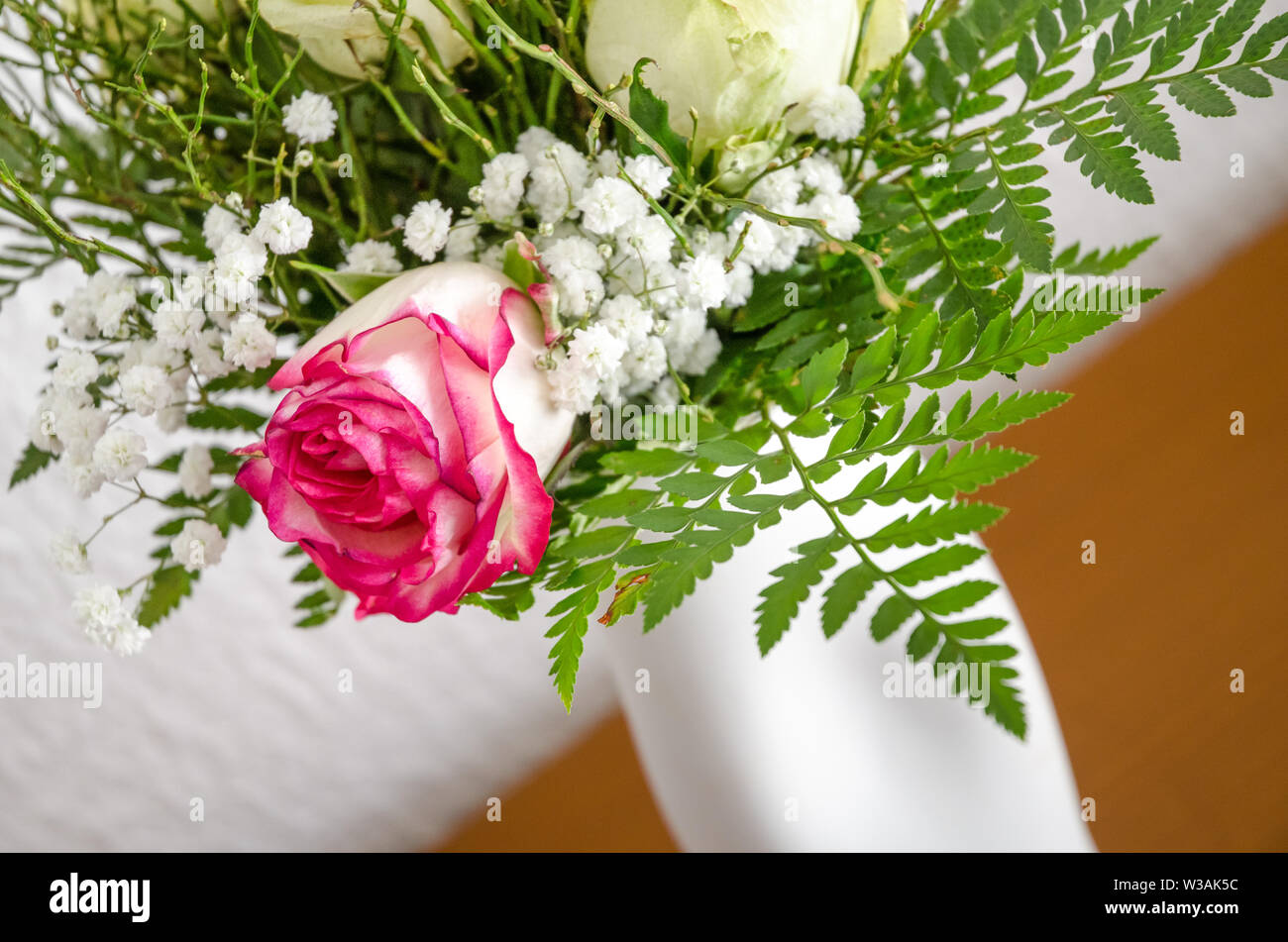 Close-up ancora vita di un fiore disposizione con le rose in un vaso bianco contro parete bianca, all'interno, soggiorno Foto Stock