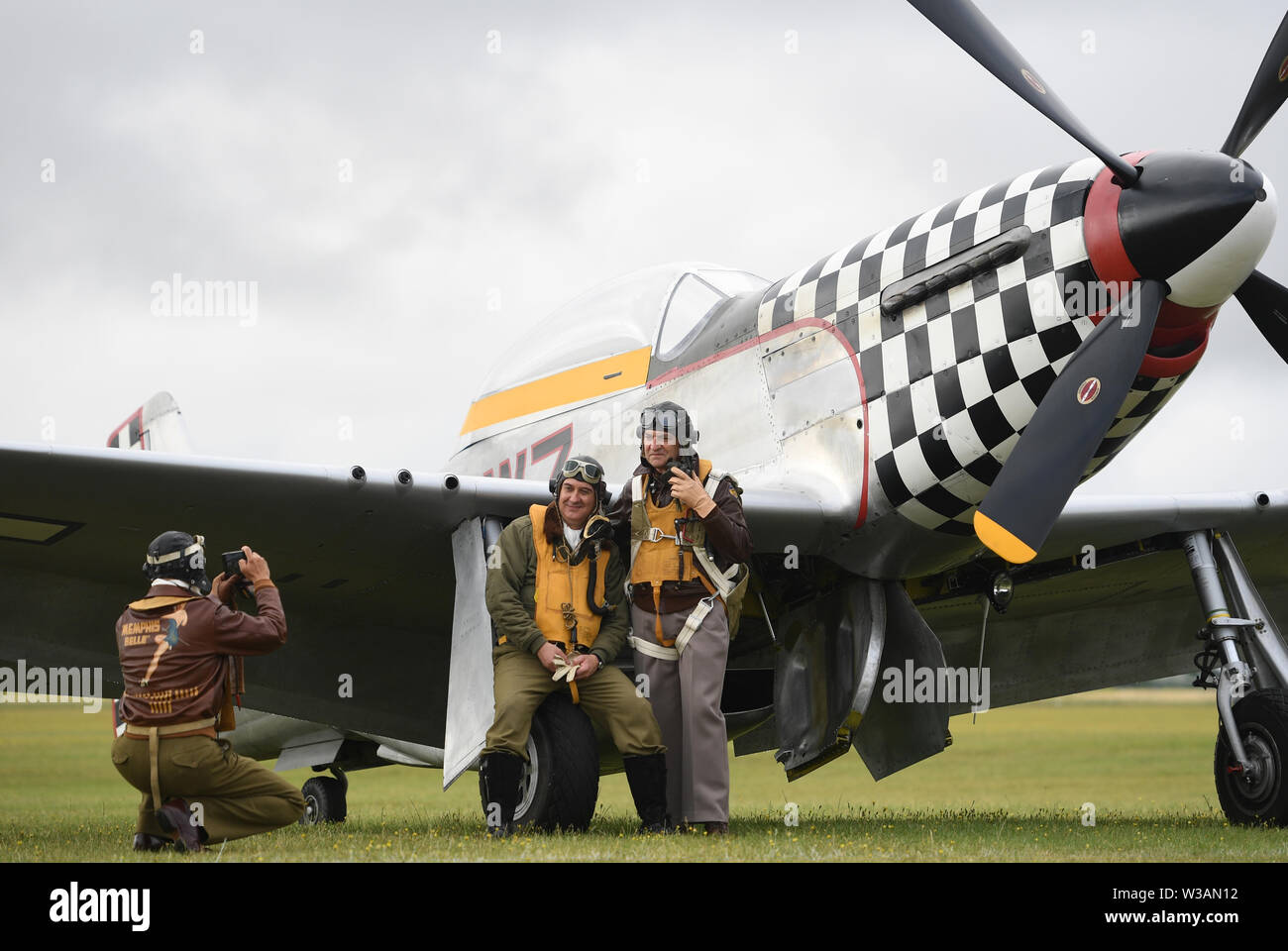 Re-enactors dagli Angeli sulla nostra ali, una seconda guerra mondiale rievocazione gruppo, posano per una foto da TF-51D Mustang 'contrario Maria' durante il Flying Legends Air Show a IWM Duxford. Foto Stock