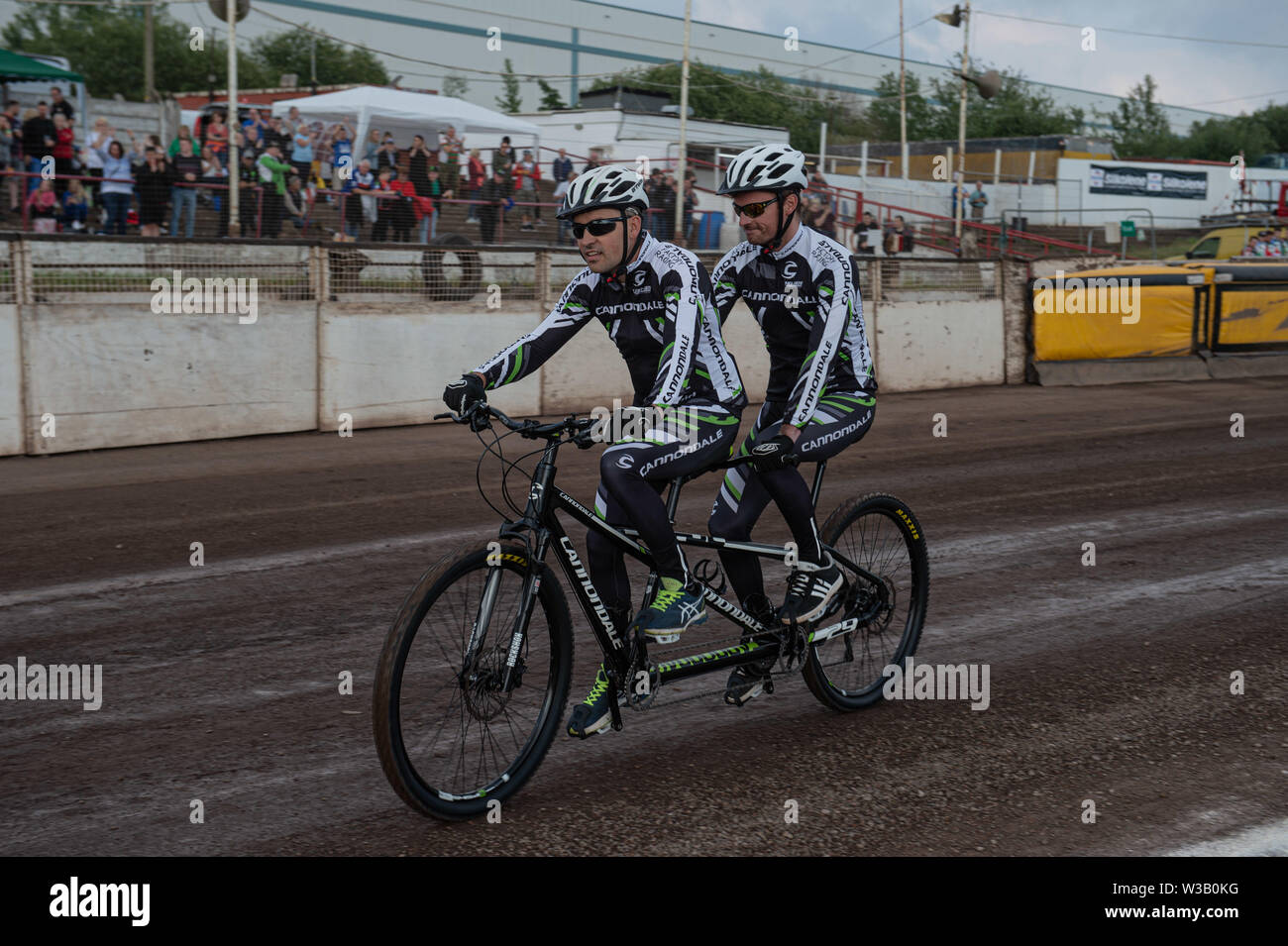 Loomer Rd, Newcastle und, UK. 13 Luglio, 2019. Stoke on Trent, 14 luglio ex pilota Ricky Ashworth (posteriore della bicicletta) con pilota Duncan Bower, fa un giro d'onore a tandem. Ricky è stato gravemente ferito e ha subito un danno cerebrale a pochi anni fa in una pista racing incidente. Parte del suo recupero è lui essendo il ÔengineÕ su Tandem durante il Campionato Nazionale 4 Team del campionato a Stoke Speedway Stadium, Loomer Rd, Newcastle Under Lyne sabato 13 luglio 2019. (Credit: Ian Charles | MI News) Credito: MI News & Sport /Alamy Live News Foto Stock