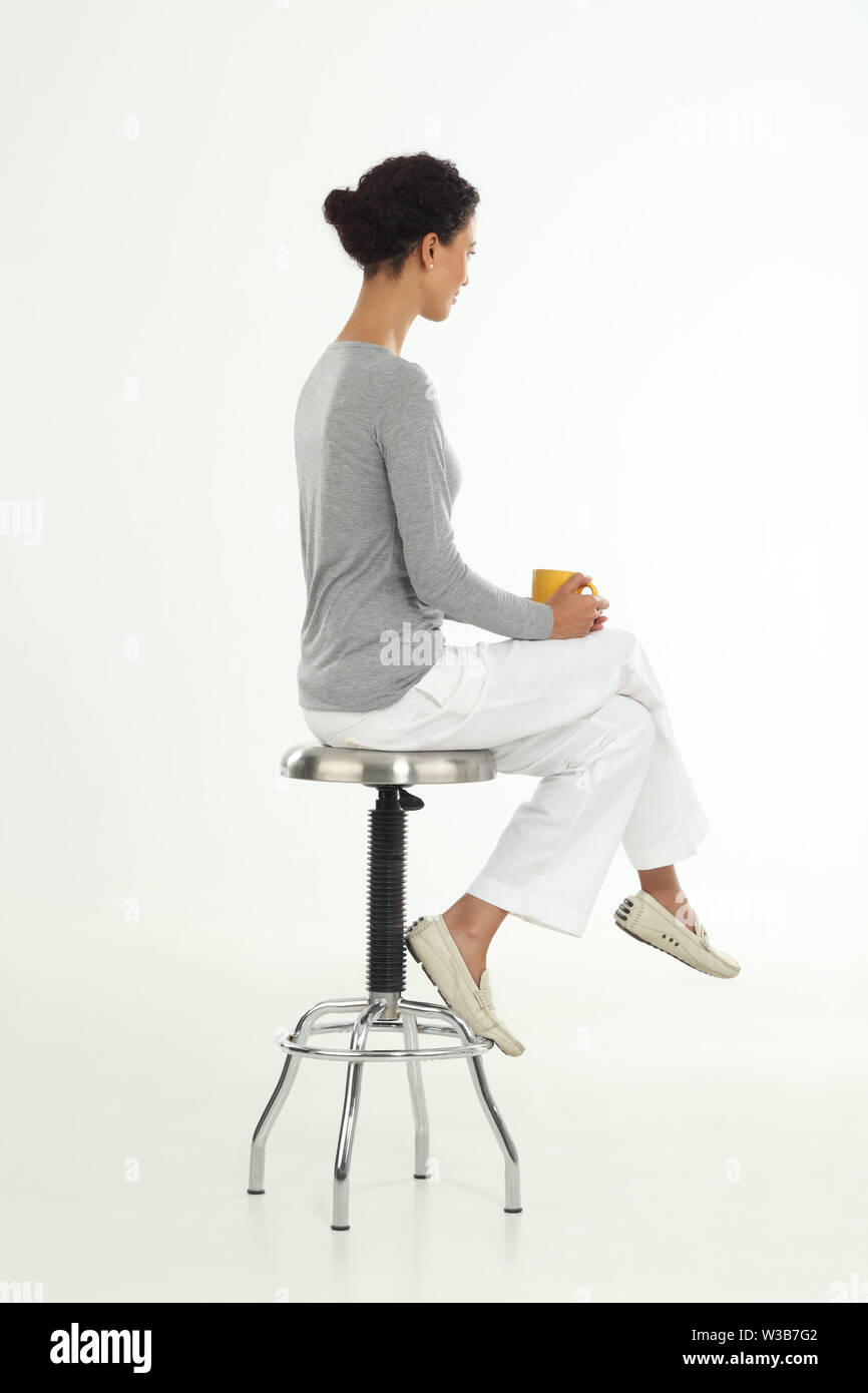 Caucasian donna seduta su uno sgabello e avente una tazza di caffè Foto Stock